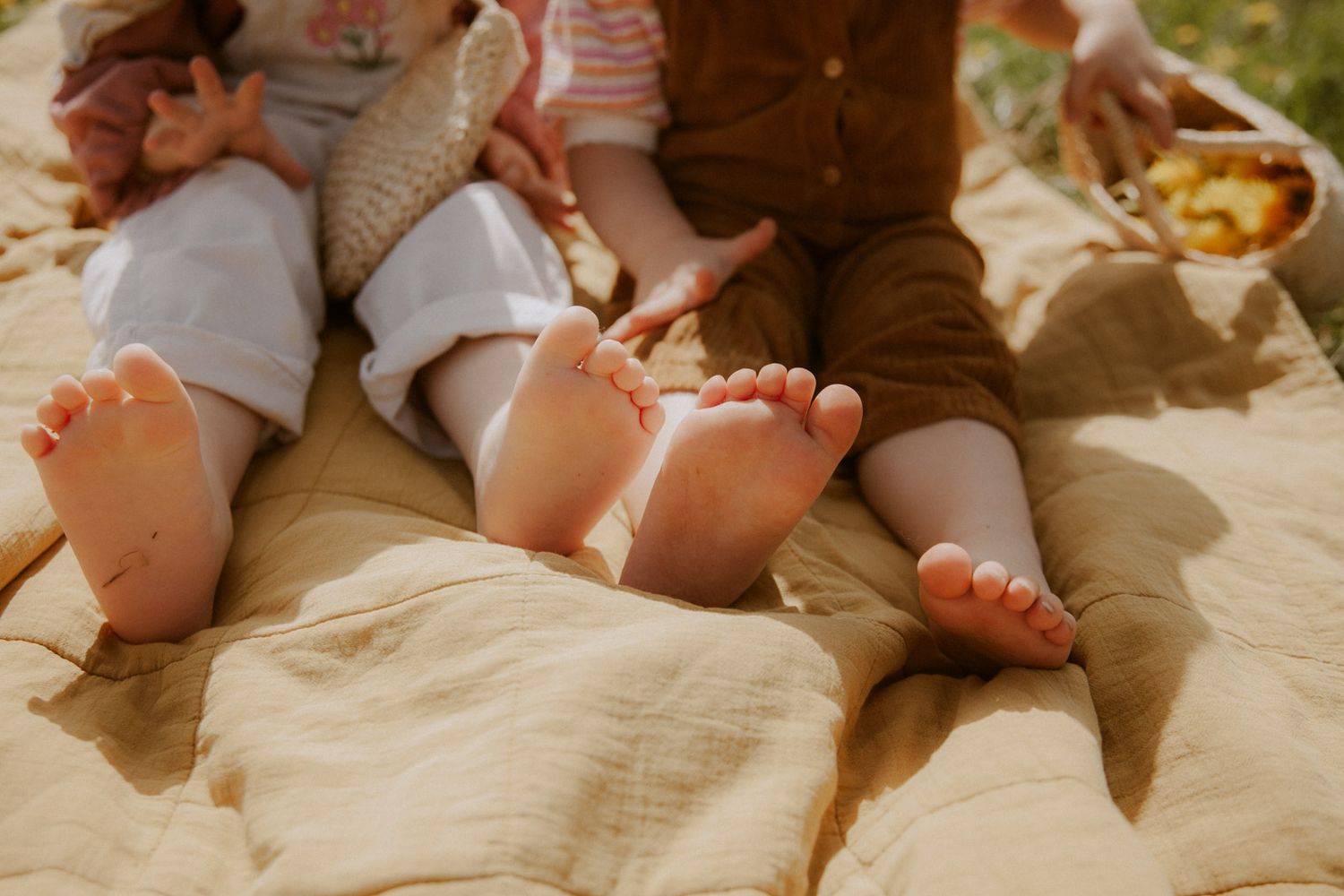 Kinderfüße zweier Geschwister auf einer Decke beim Picknick