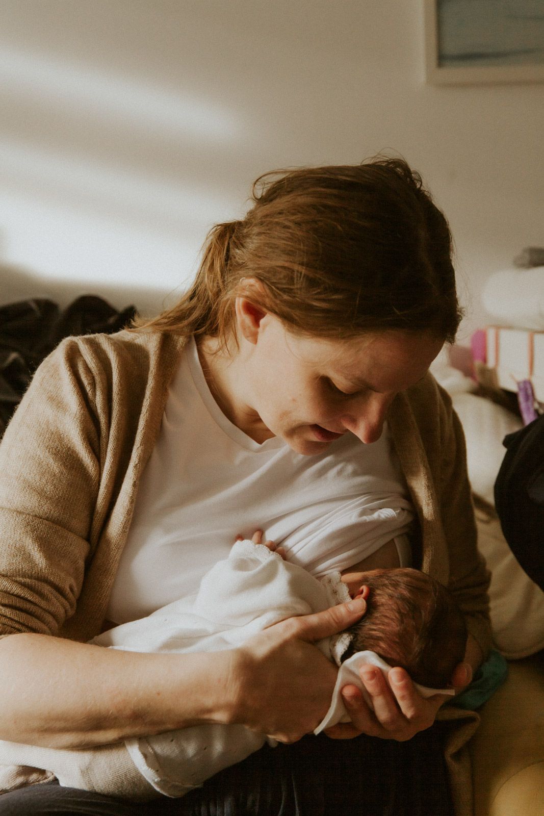 Mutter stillt ihr Neugeborenes liebevoll – authentische Neugeborenenfotografie