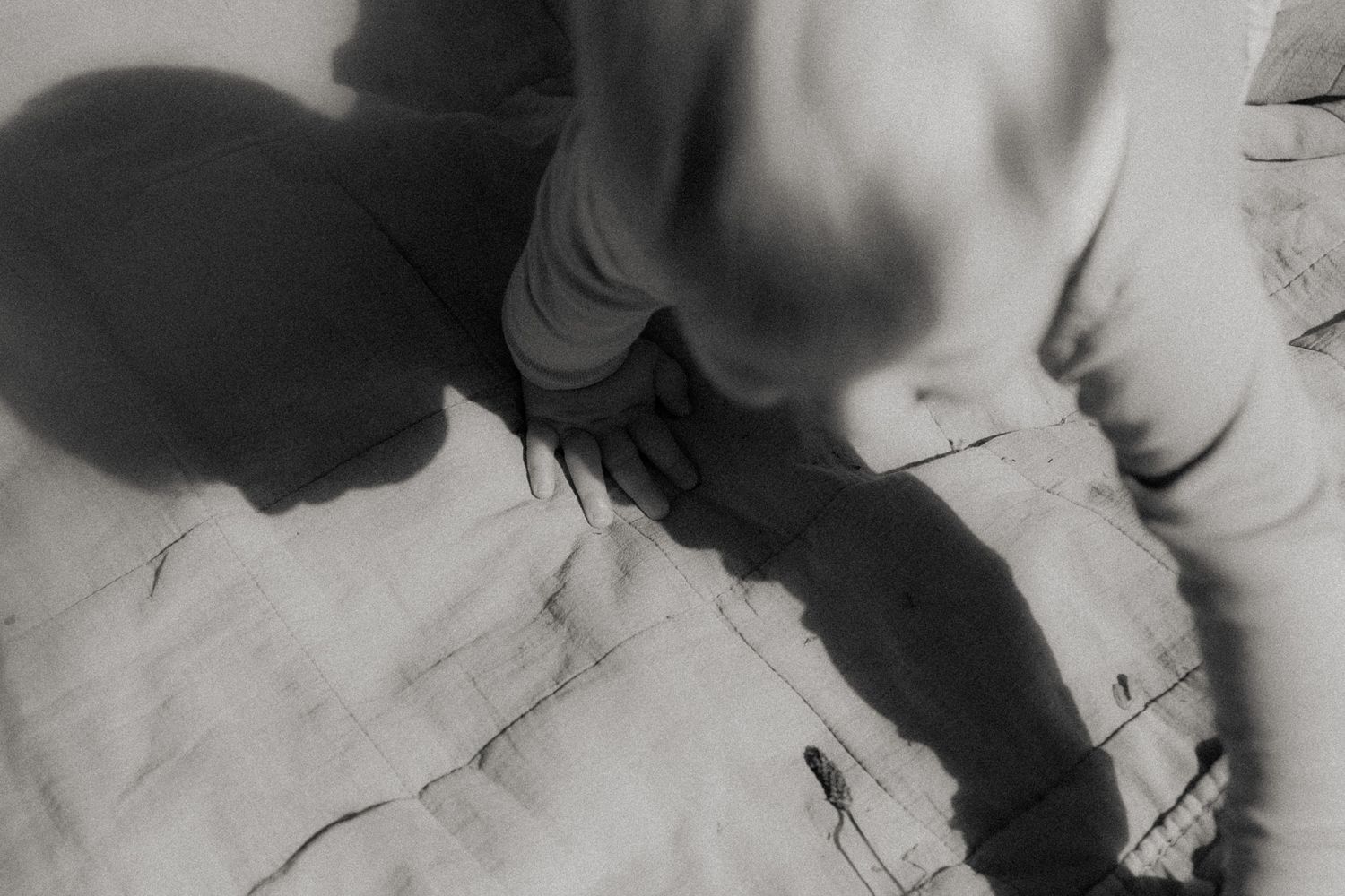Schatten auf einer Decke eines Babys – Schwarz-Weiß Neugeborenenfotografie Denise Haberl