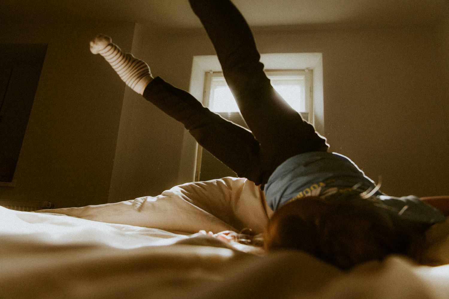 Kind liegt wild auf dem Bett und strampelt mit den Beinen