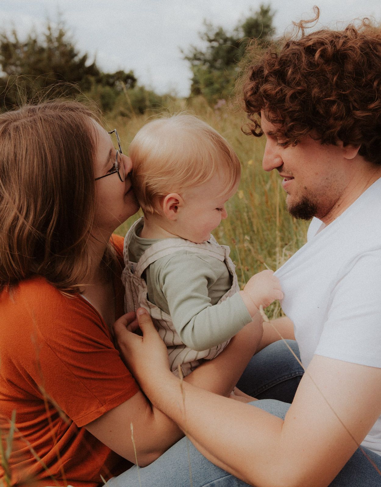 Familie küsst gemeinsam ihr Baby in der Natur – Familienshooting Bayern