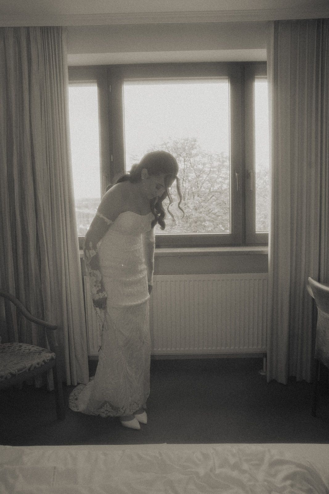 Braut richtet ihr Kleid im Hotelzimmer – Getting Ready Hochzeitsfotografie