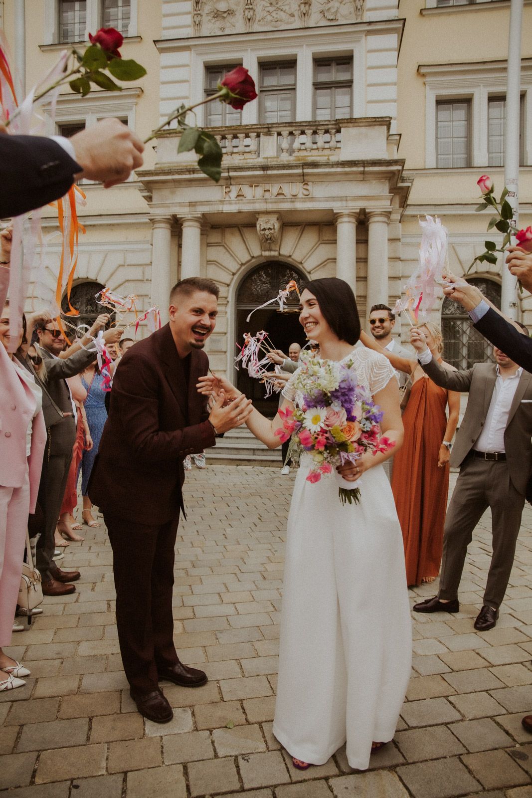 Gäste feiern das Brautpaar vor dem Rathaus mit bunten Blumen – Hochzeit Ingolstadt