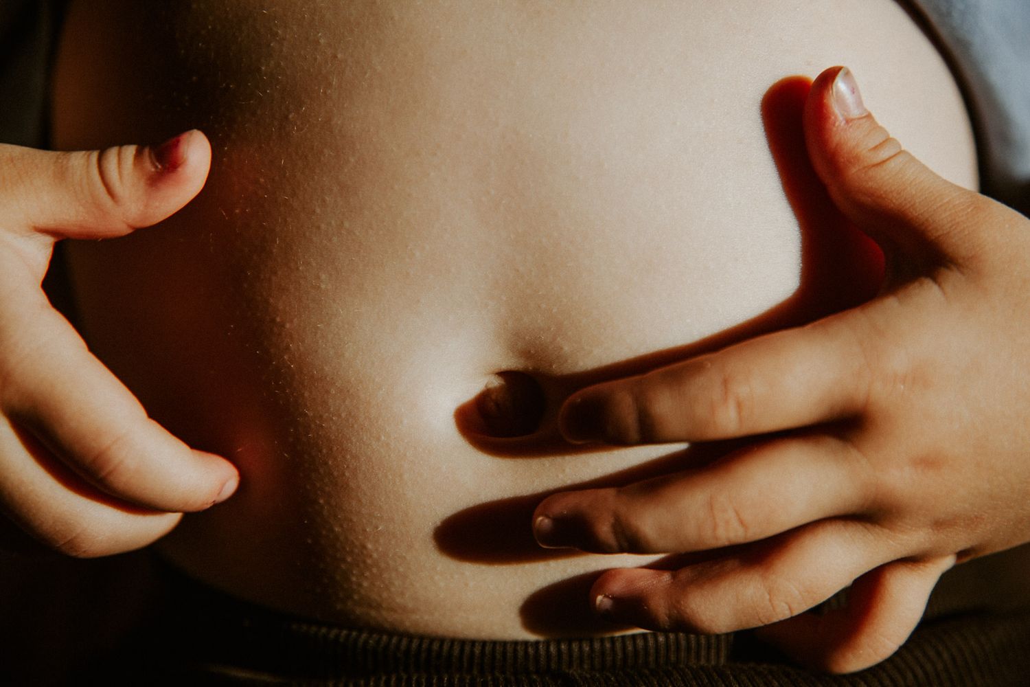 Kind berührt neugierig seinen Bauch