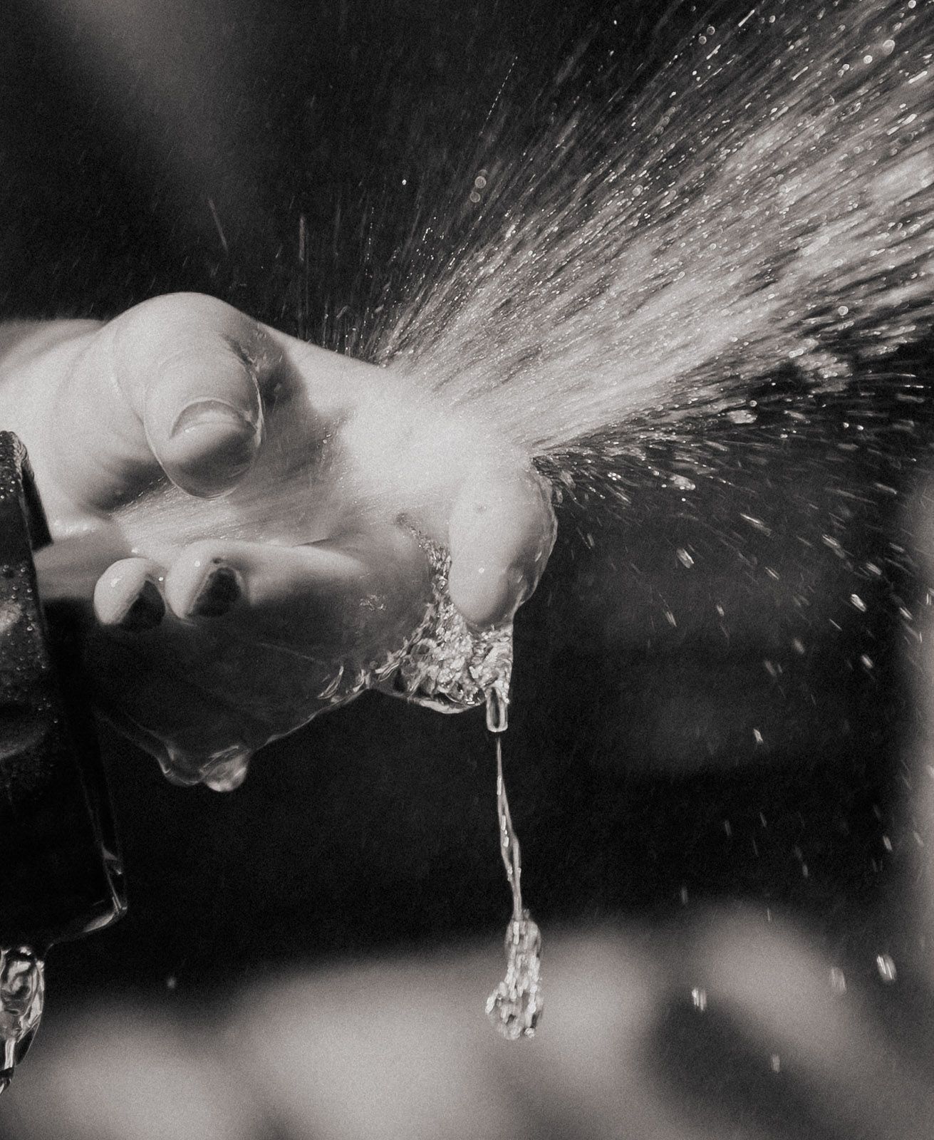 Schwarz-Weiß Aufnahme einer Hand die Wasser spritzt