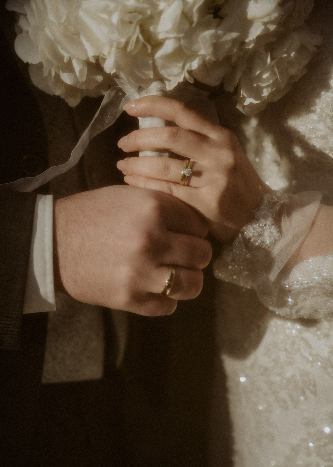 Brautpaar hält Hände mit Eheringen und Brautstrauß – Detailaufnahme Hochzeit