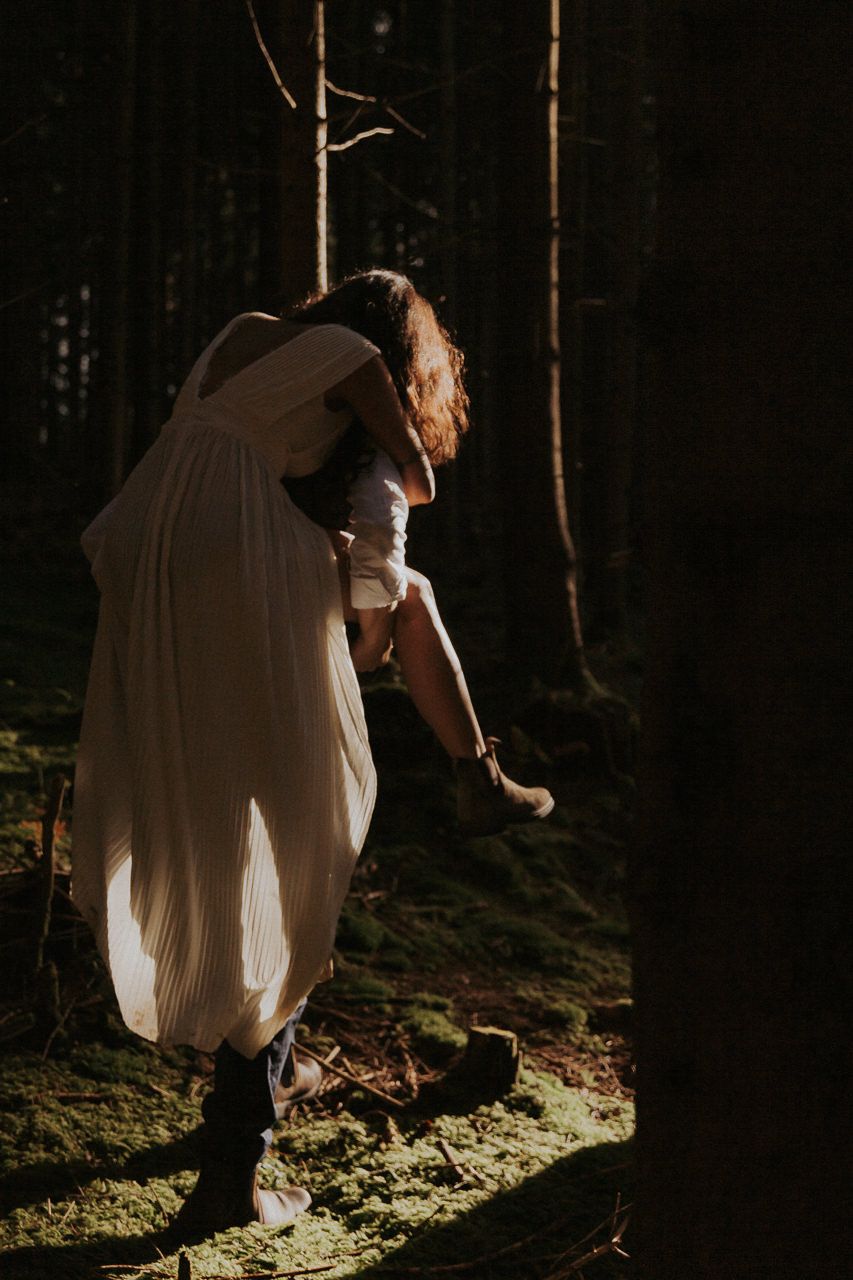 Braut tanzt ausgelassen im Gegenlicht in einem dunklen Wald