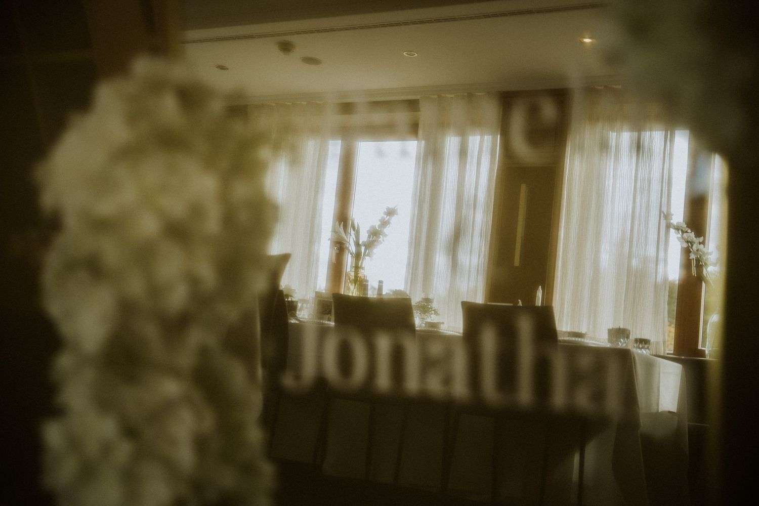 Hochzeitsdekoration mit weißen Blumen und Namensschild am Fenster