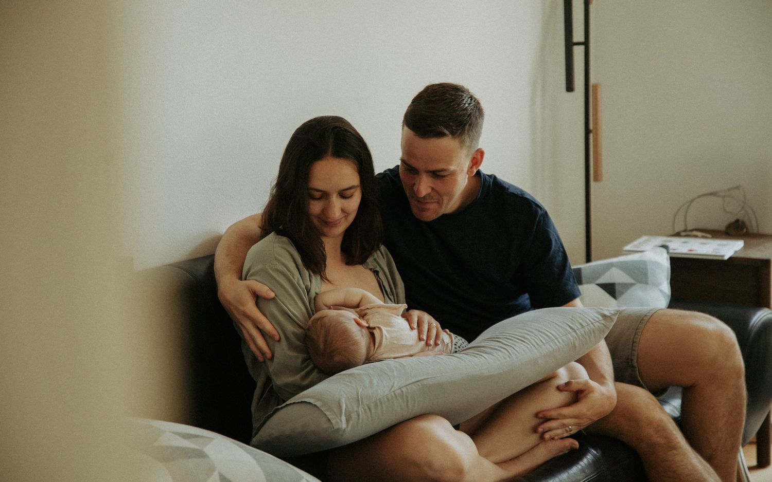 Eltern sitzen gemeinsam und bewundern ihr Neugeborenes zuhause