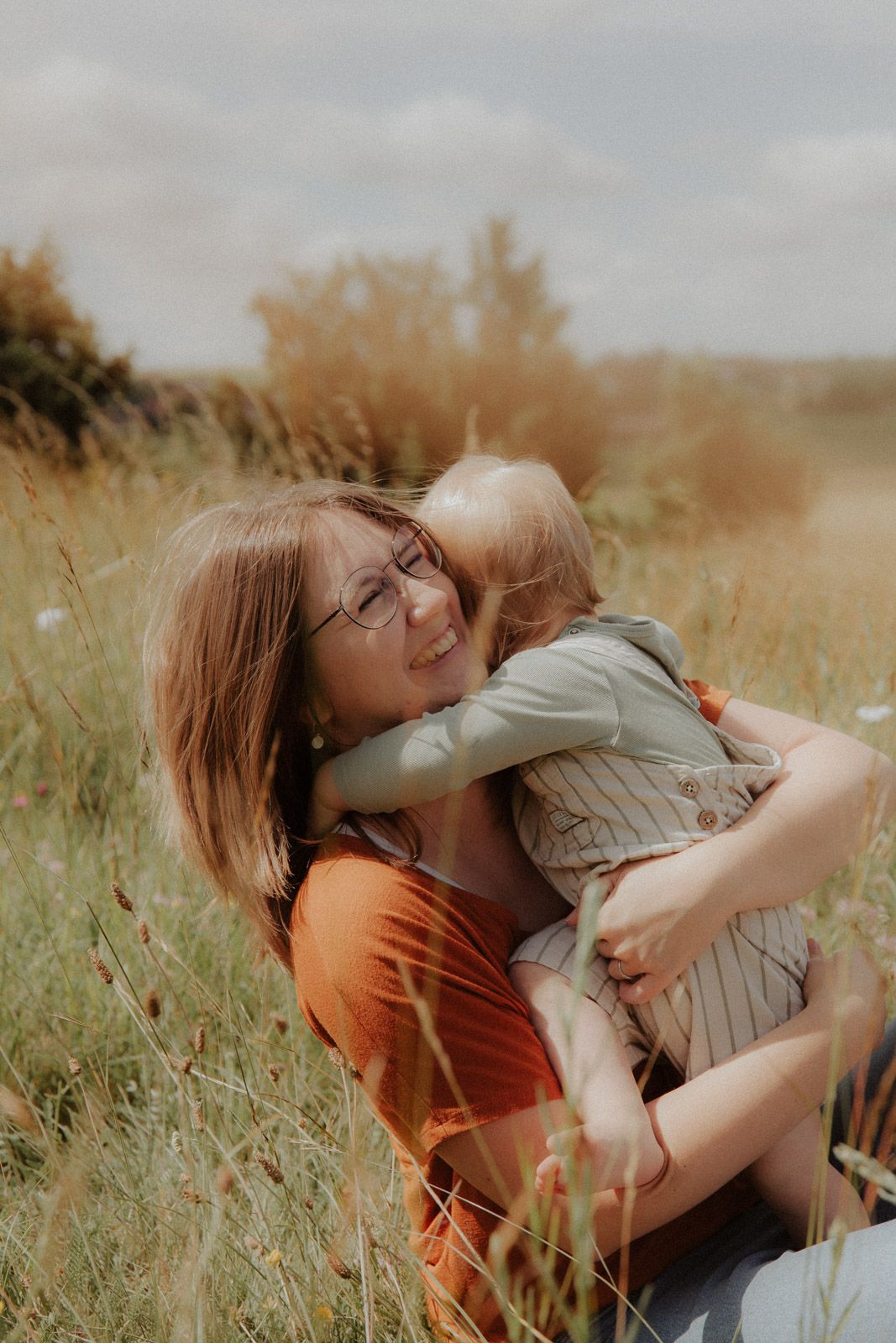 Mutter lacht glücklich während ihr Kind sie von hinten umarmt – Familienfotografin Ingolstadt
