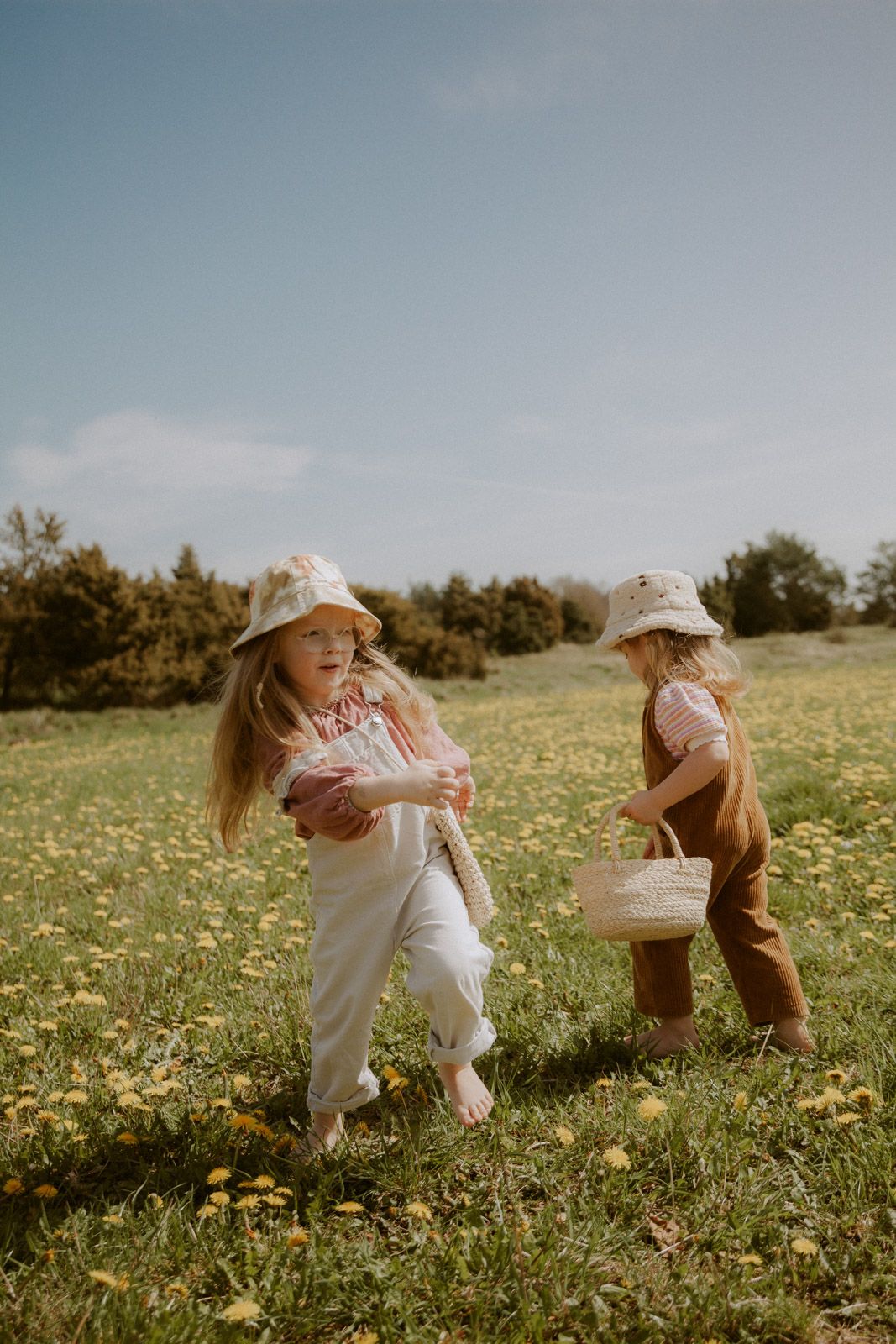 Zwei Mädchen laufen mit Körben über eine Blumenwiese – Kinderfotografie Ingolstadt