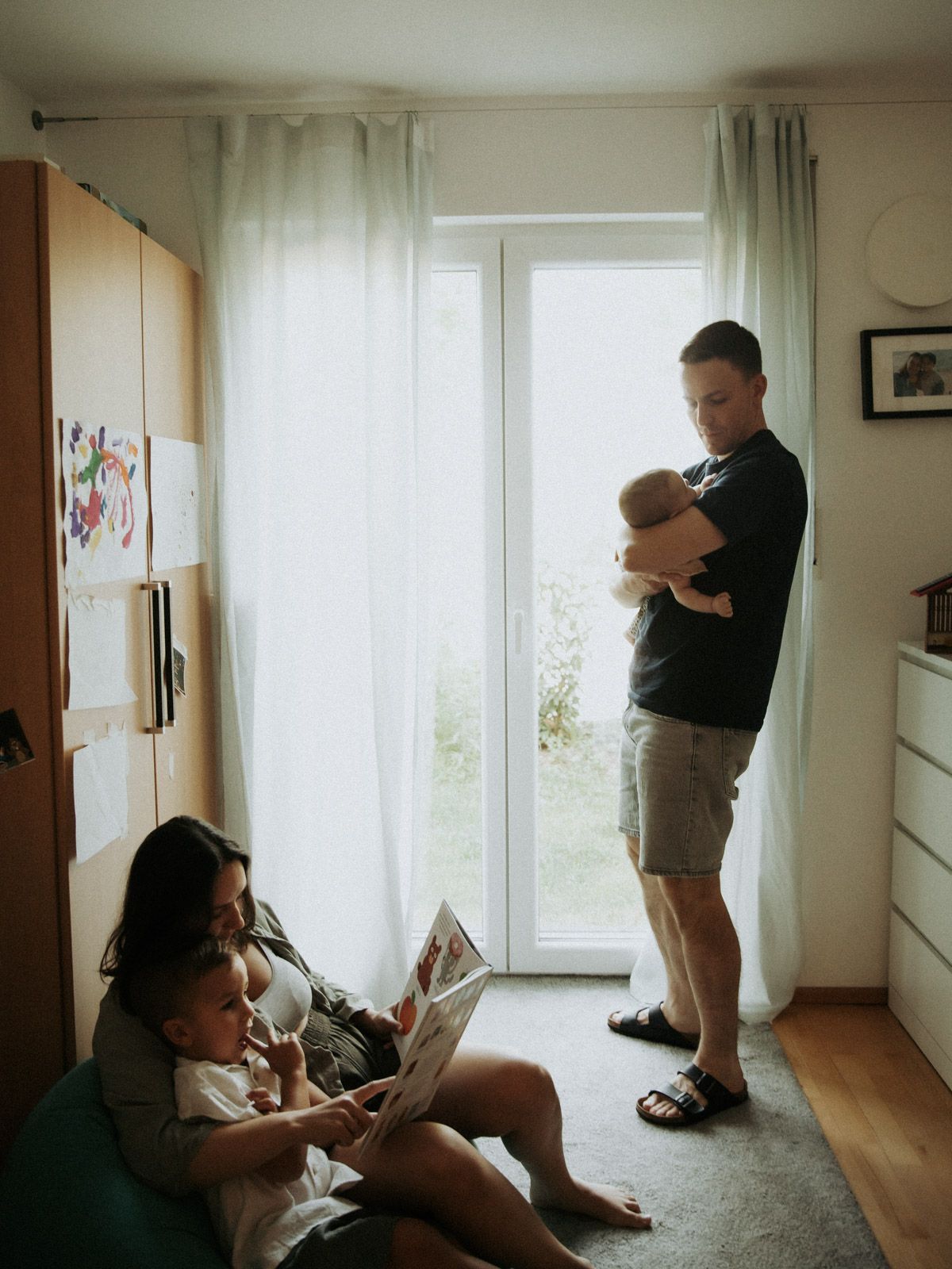 Familie genießt einen ruhigen Morgen zuhause – Vater hält Baby während Mutter liest