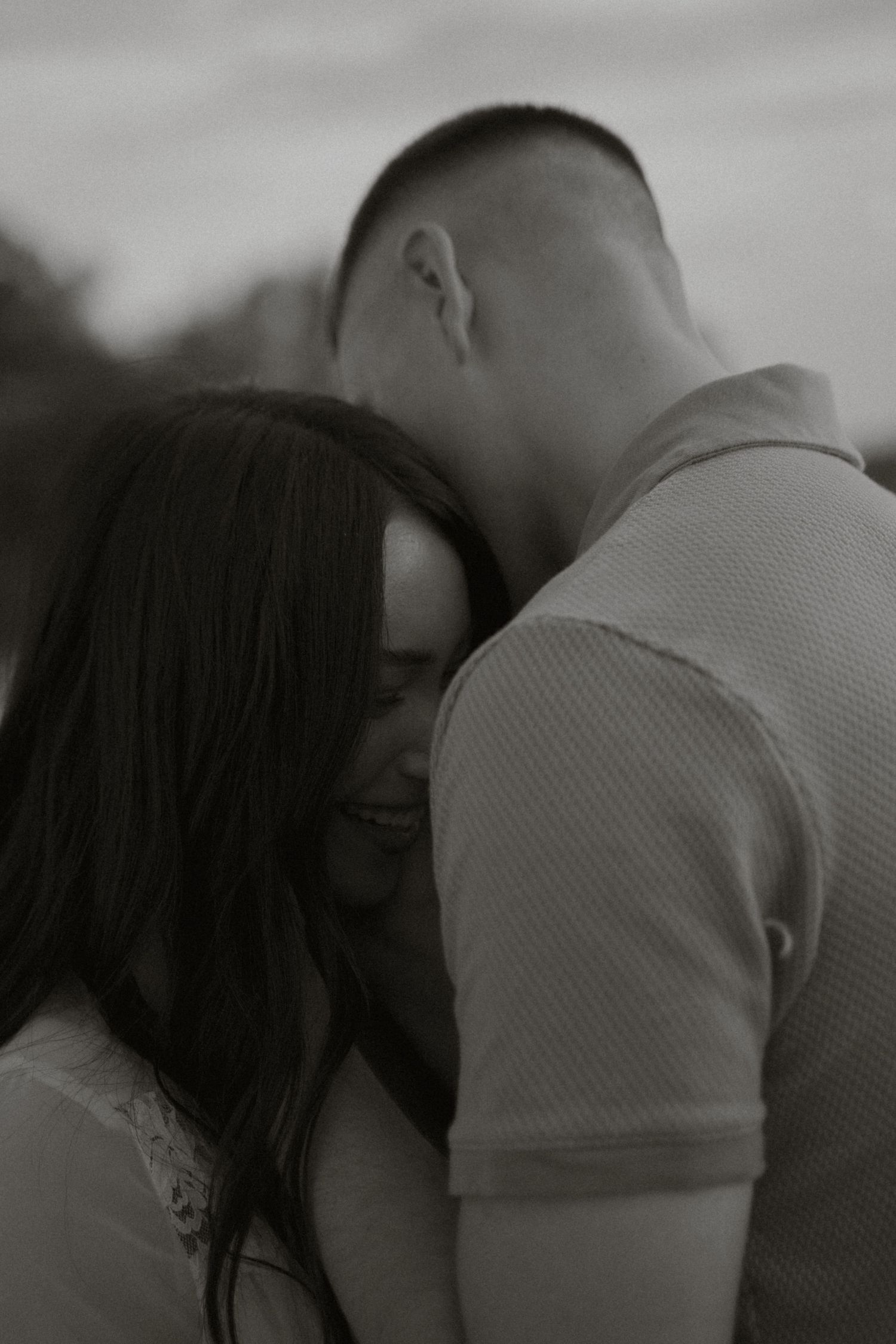 Black and white photo of couple sharing tender romantic moment outdoors.