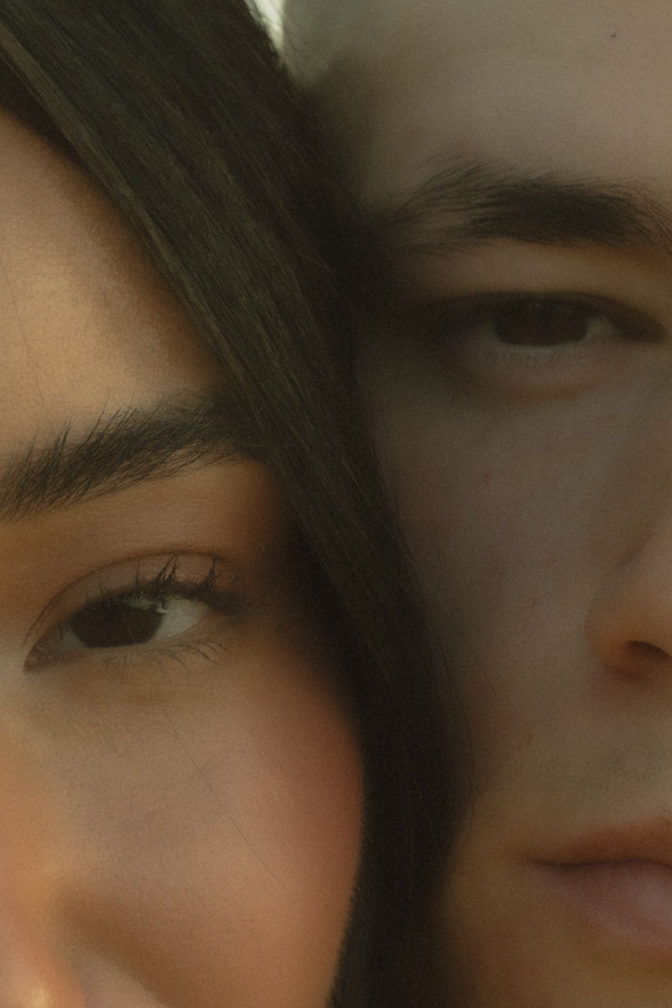 Intimate close-up portrait of couple with faces together in soft light.
