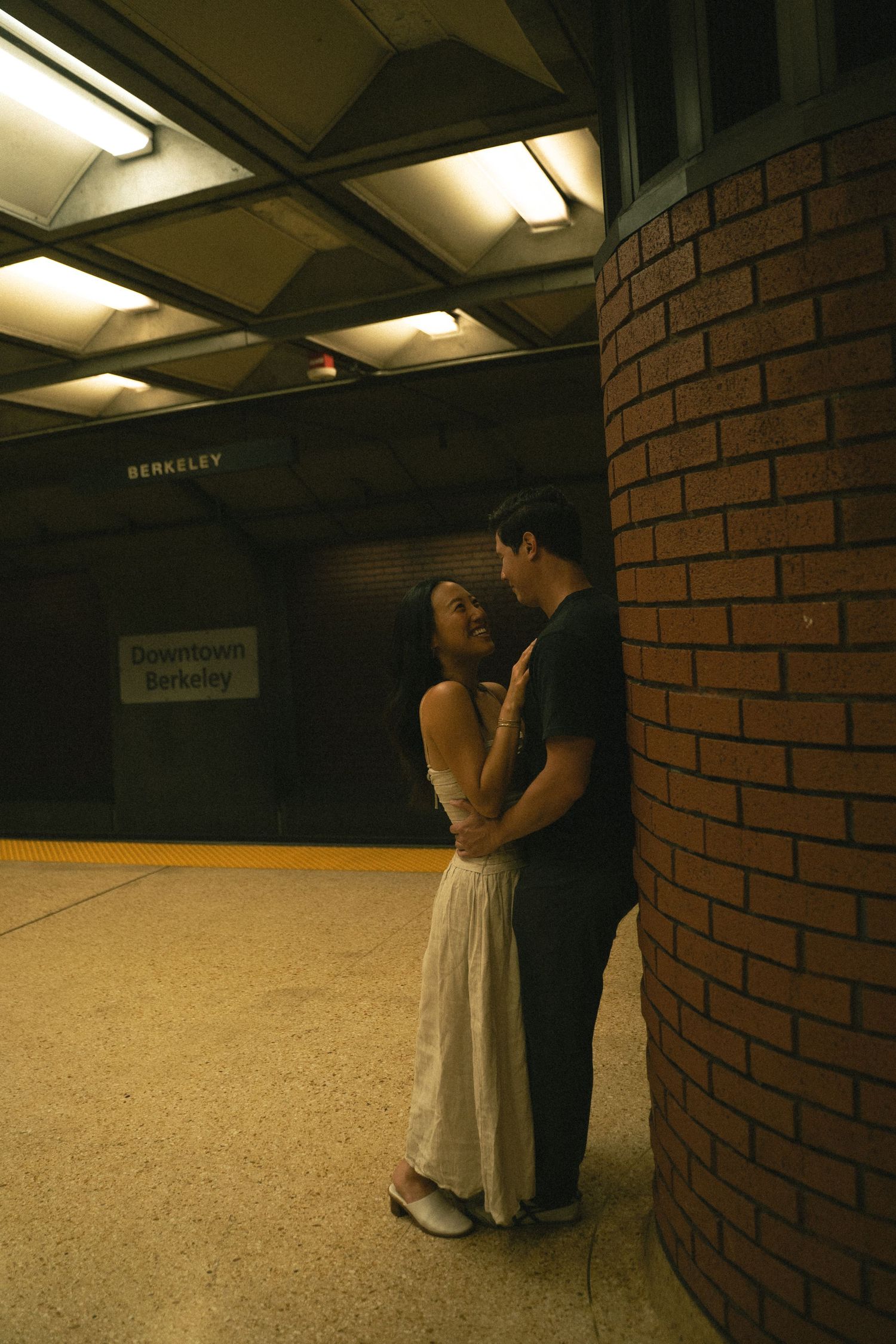 Couple sharing a romantic moment at Downtown Berkeley BART station platform.