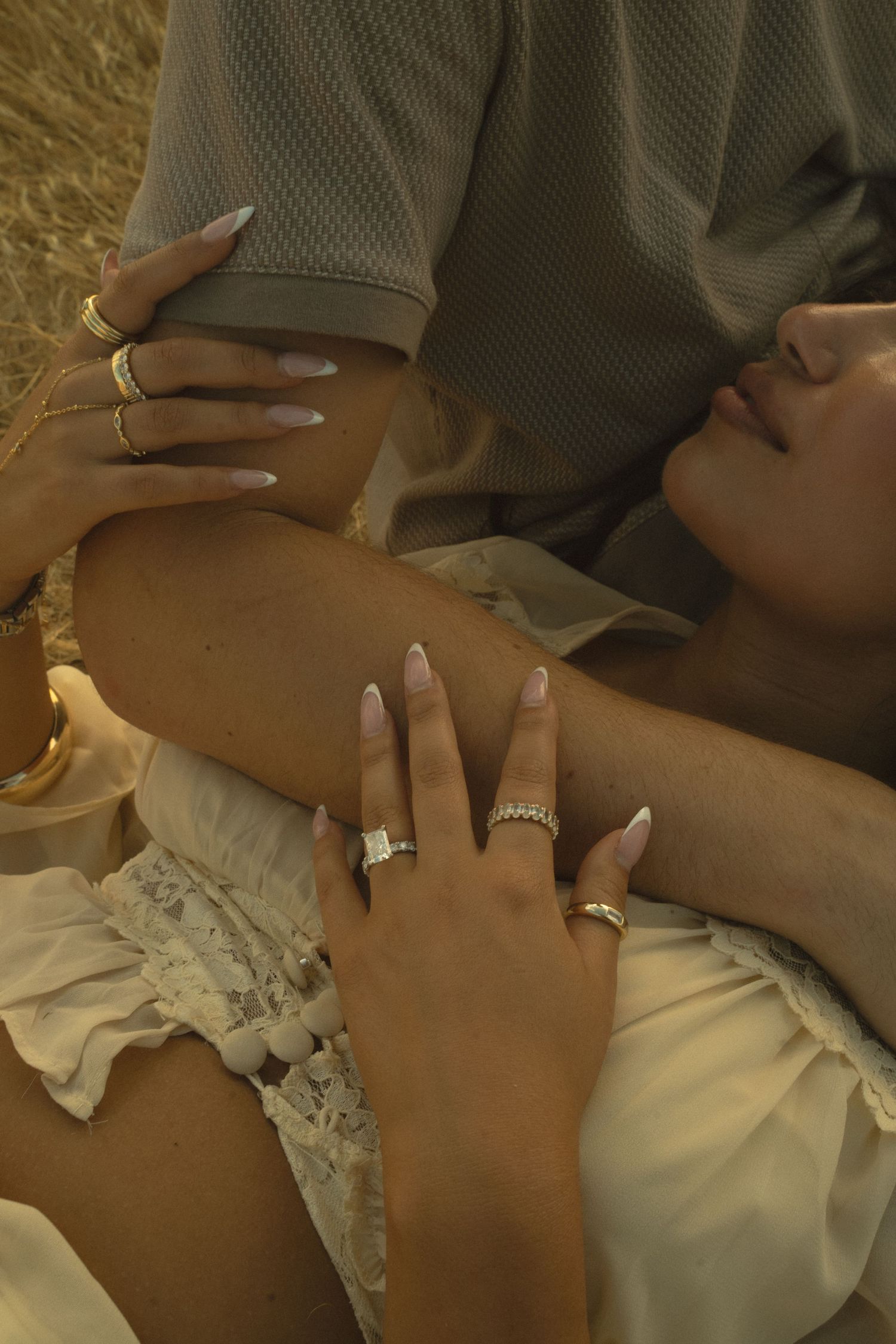 Close-up of womans hands adorned with engagement ring and gold jewelry.