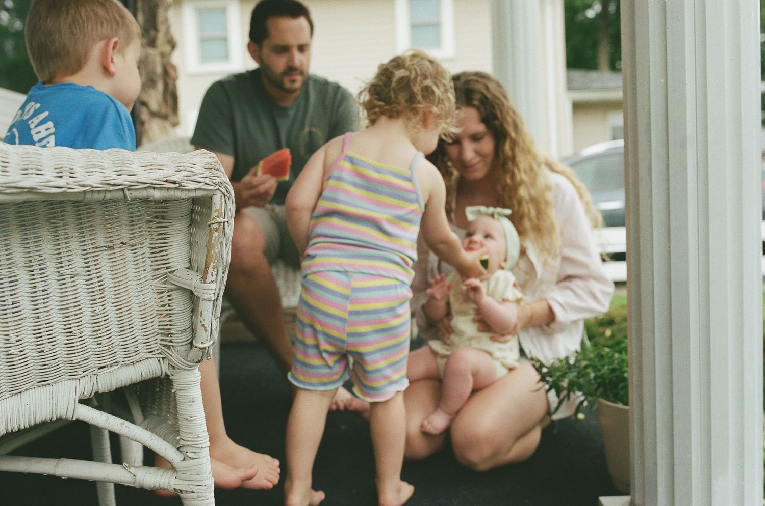 Family with young children sharing a tender moment on a cozy front porch.
