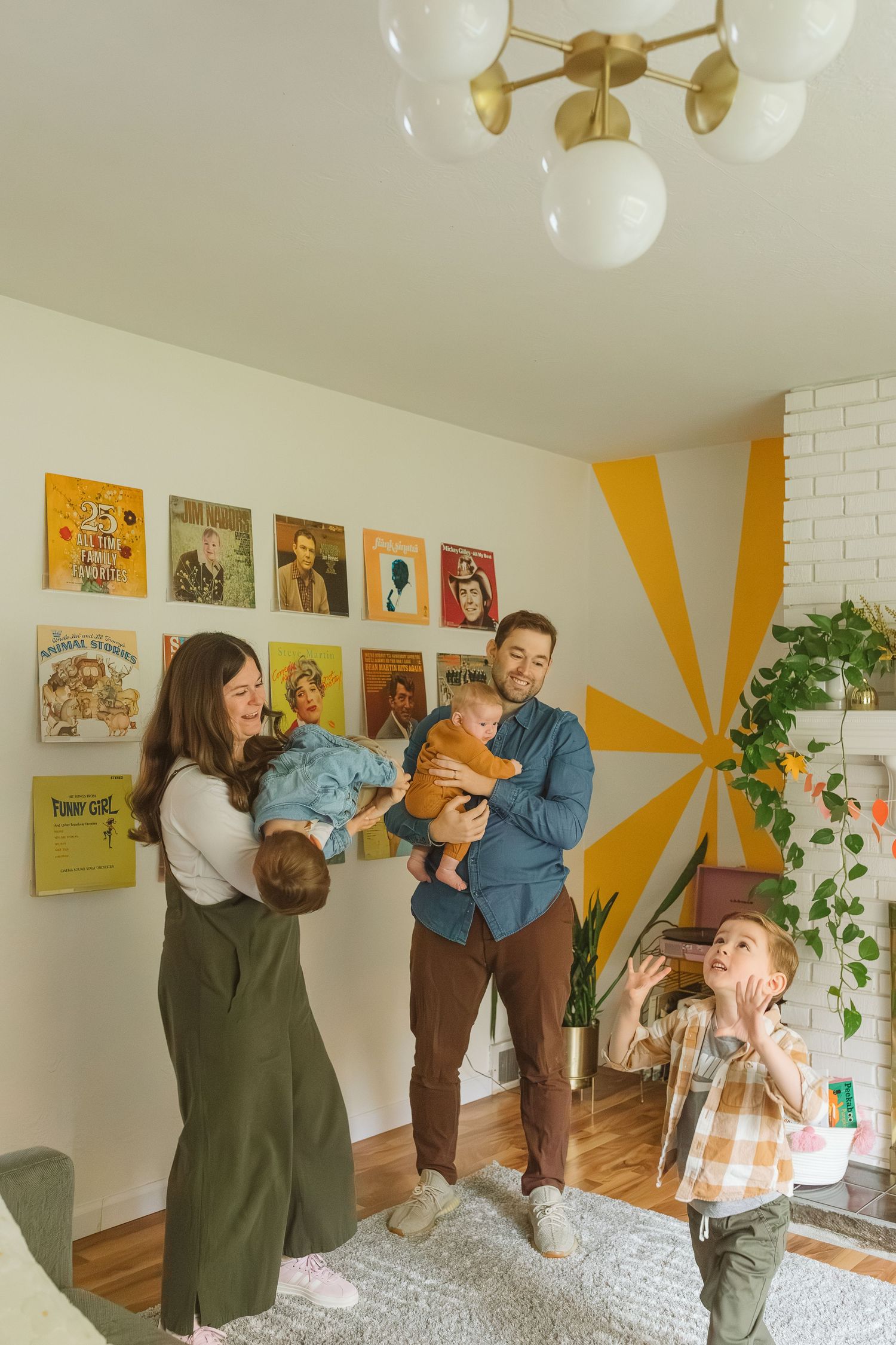 Family of five in a colorful retro-styled living room with vinyl records displayed on the wall.
