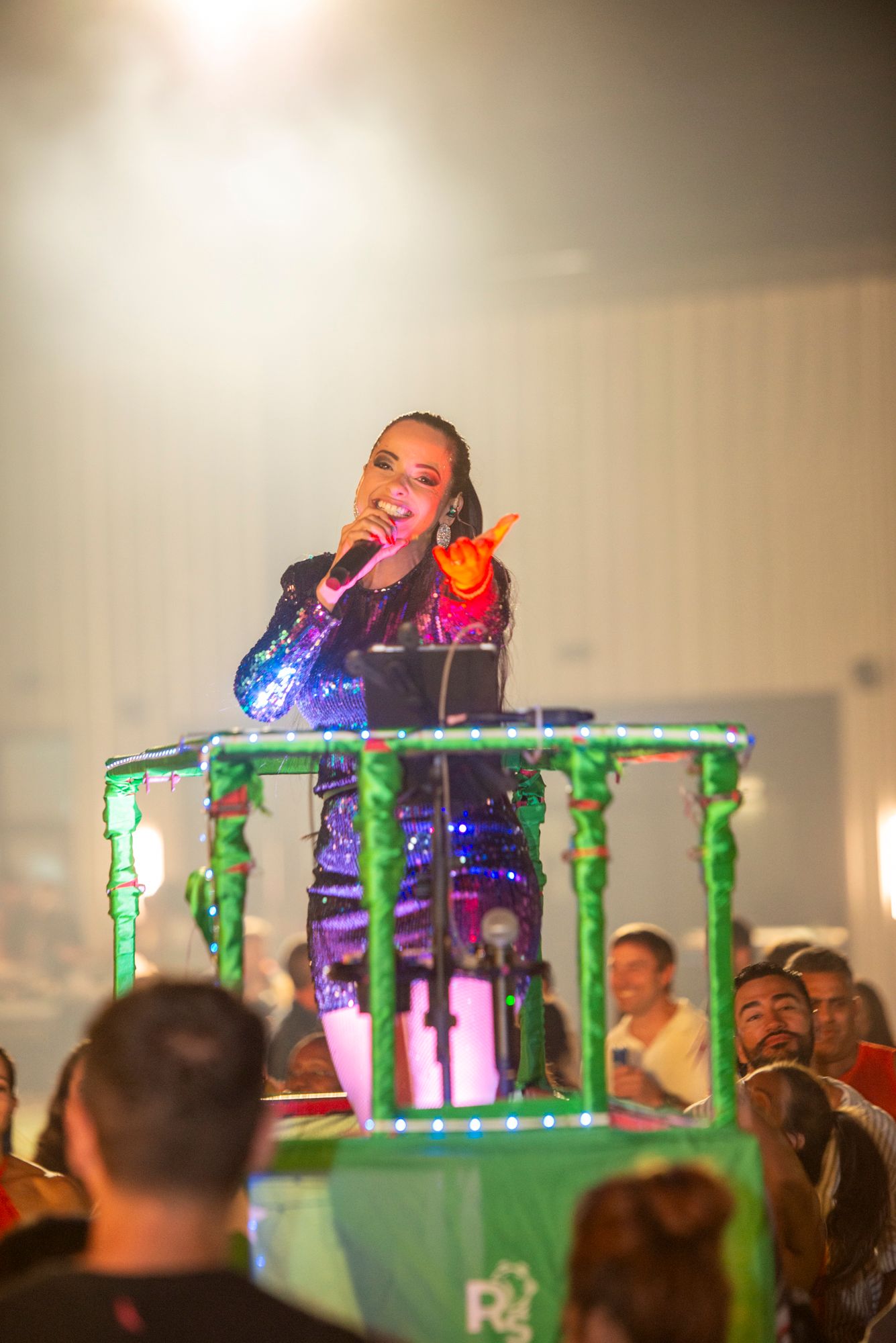 Female singer in sequined outfit performing on a decorated carnival float.
