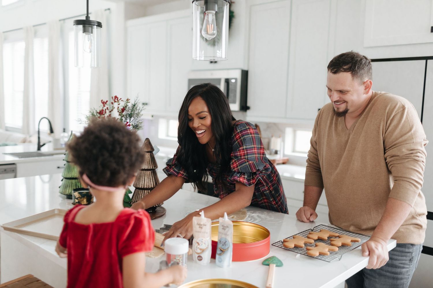 Family baking Christmas cookies together in a bright white kitchen, smiling and sharing holiday traditions.