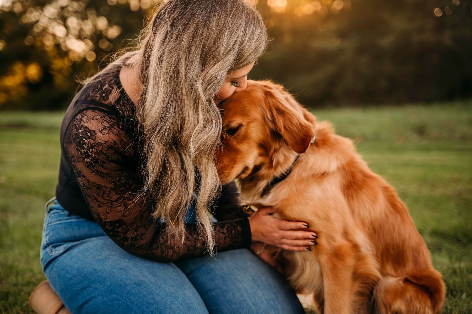 Blonde woman in lace top lovingly nuzzling a Golden Retriever dog outdoors at sunset in Millwood Virginia