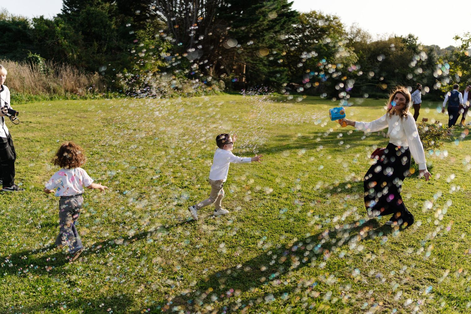 Enfants jouant dans le jardin du Domaine Saint Laud à Angers lors d’un mariage – Photographie de mariage champêtre avec bulles de savon.