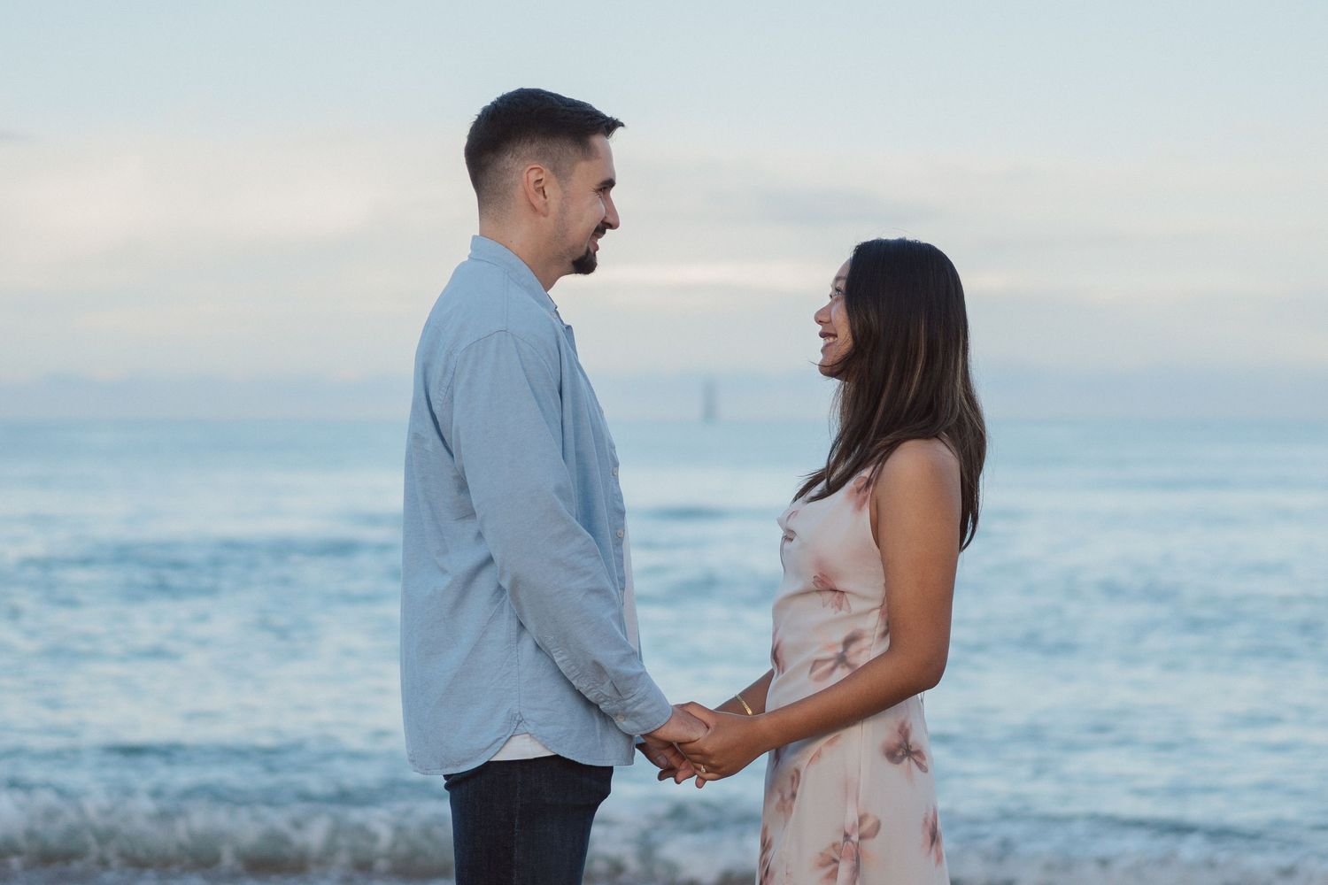 Couple de futurs mariés sur la plage aux Sables d’Olonne, se regardant tendrement au coucher du soleil