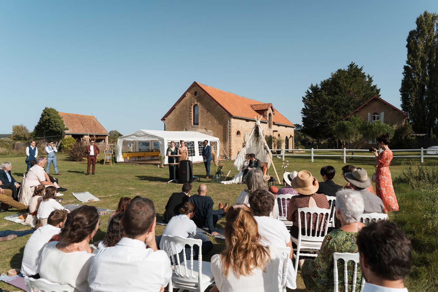 Cérémonie laïque en plein air au Domaine Saint Laud à Angers – Invités assis face aux mariés dans un cadre champêtre.