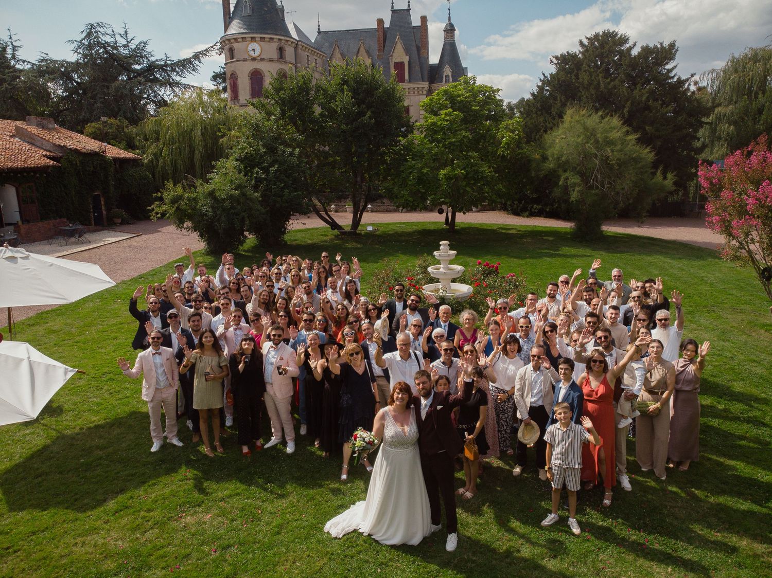 Photo de groupe de mariage devant le Château des Landes à Cléré-sur-Layon – Vue grand angle avec les invités rassemblés autour des mariés.