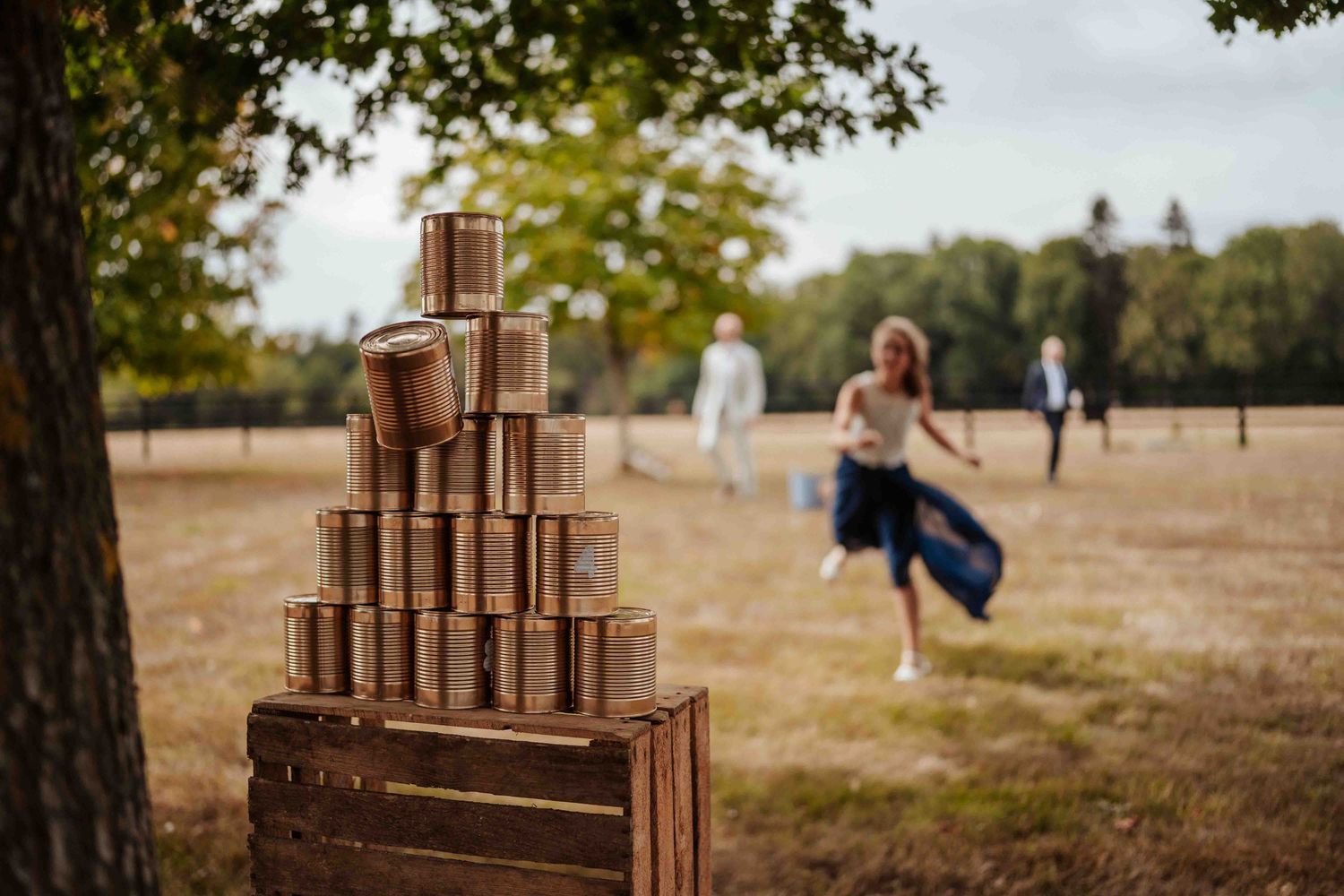 Pyramide de boîtes de conserve dorées sur des caisses en bois, dans une aire de jeux extérieure pour un mariage.