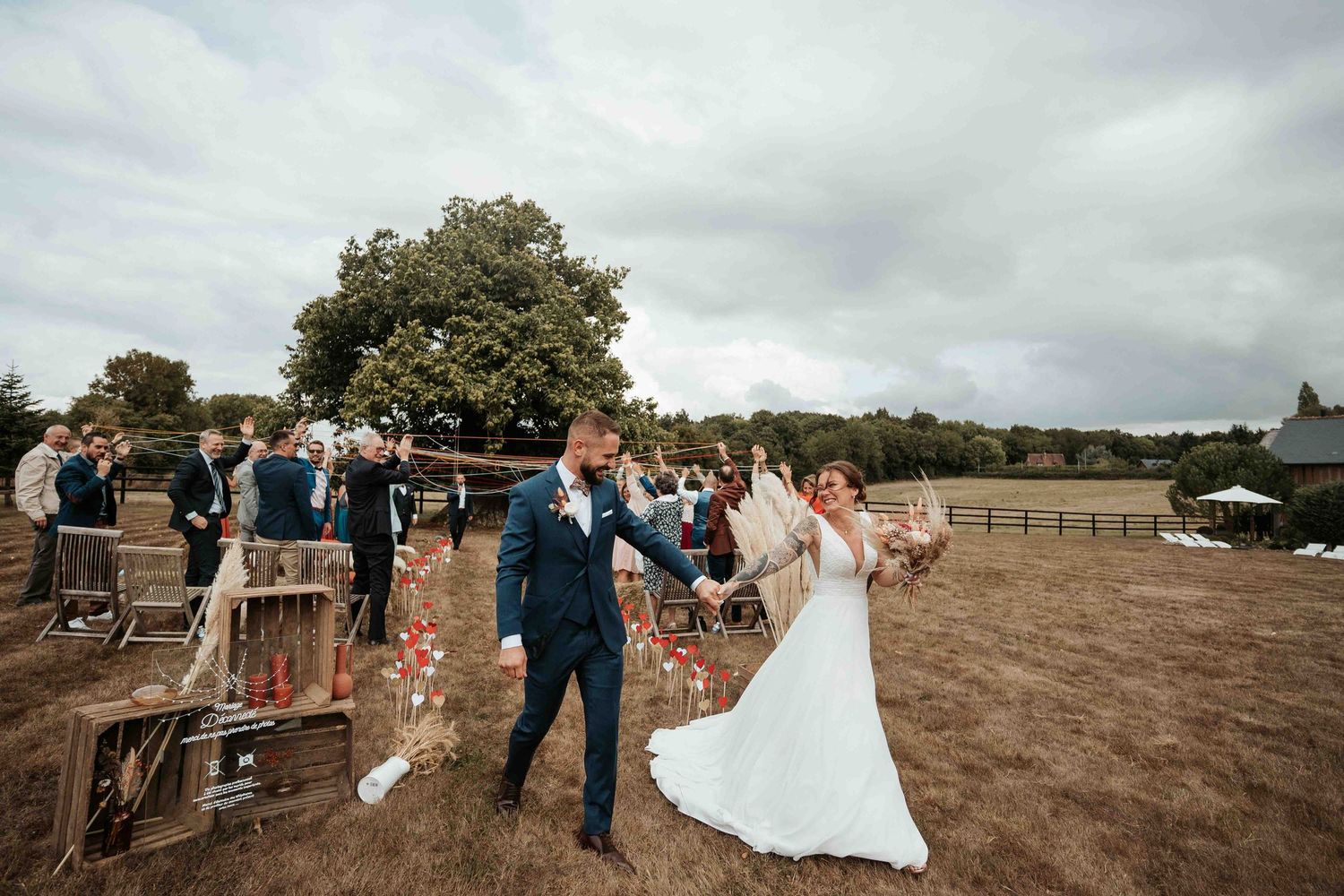 Les mariés célèbrent leur union dans un lieu de mariage champêtre en plein air, le marié faisant tournoyer la mariée par la main.