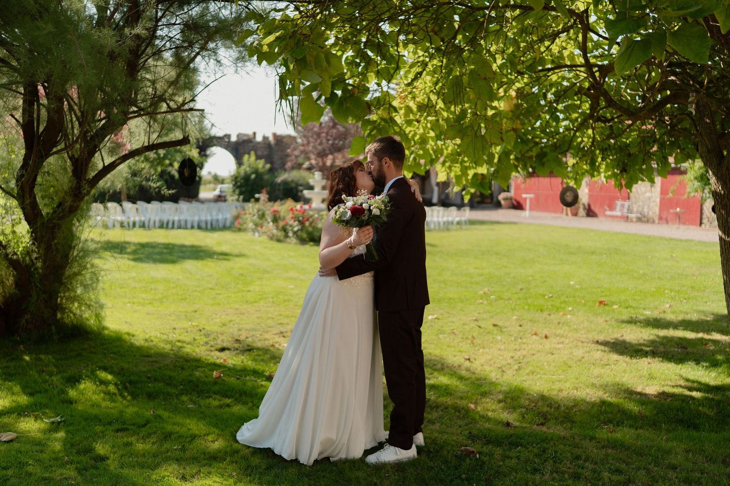 Mariés s’embrassant sous les arbres du parc du Château des Landes à Cléré-sur-Layon – Photographie romantique en lumière naturelle.