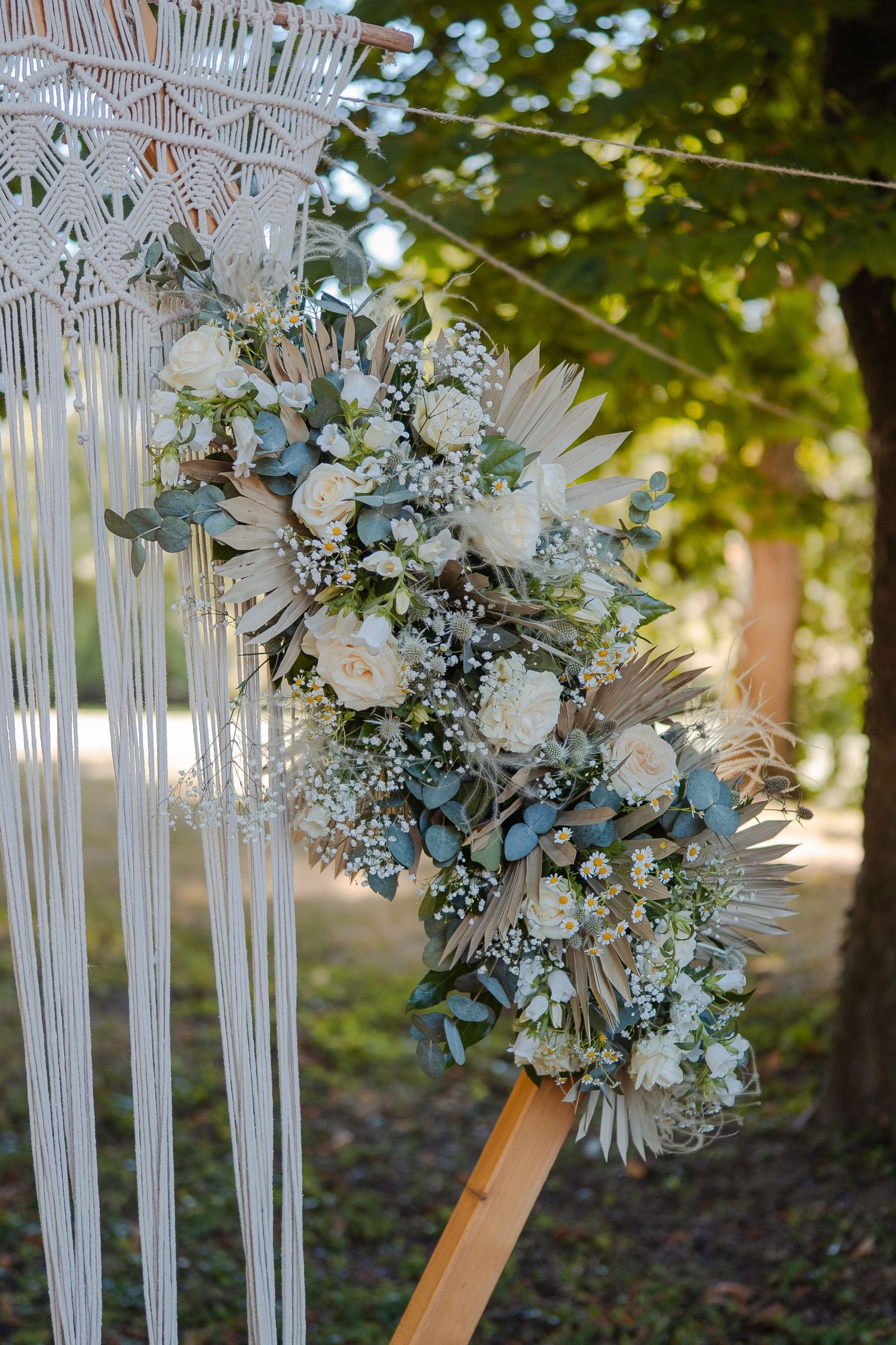 Détail de macramé et fleurs blanches pour décoration de mariage – Roses, eucalyptus et gypsophile sur support en corde, ambiance bohème.