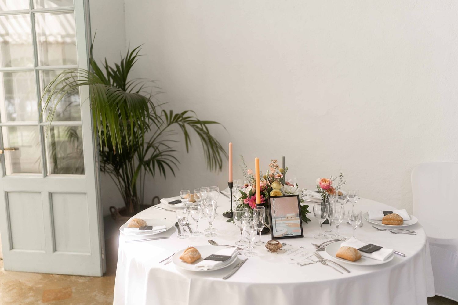 Élégante table de réception de mariage avec nappes blanches, bougies, centre de table floral et couverts.