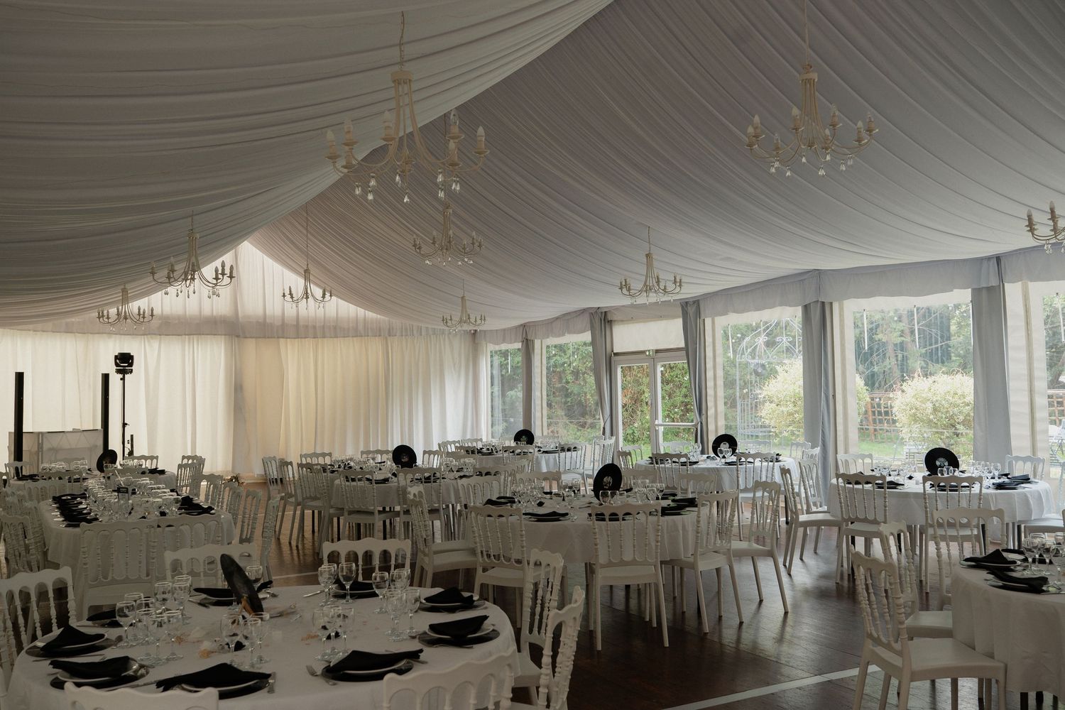 Salle de réception décorée pour un mariage au Château des Landes à Cléré-sur-Layon – Tables dressées sous un plafond drapé blanc avec lustre