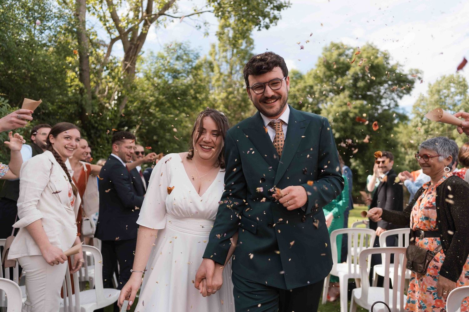 Après leur cérémonie de mariage, les jeunes mariés traversent une pluie de confettis colorés à l'extérieur.