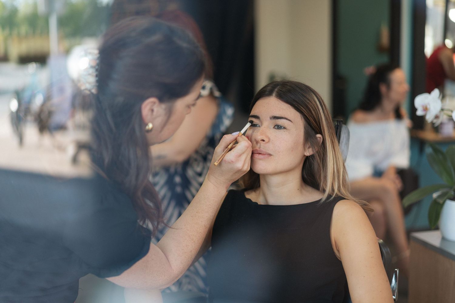 Professional makeup artist applying makeup to a young woman in a modern beauty salon.