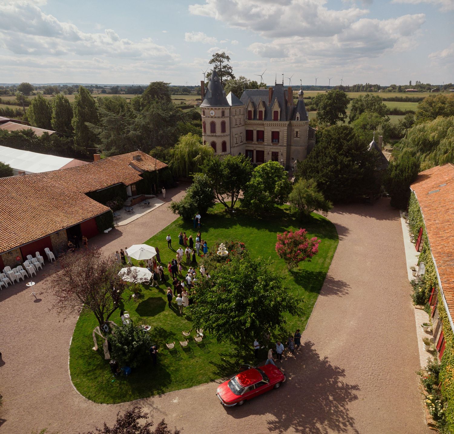 Photo de mariage au drone – Vue aérienne du Château des Landes et de ses invités dans le jardin – Panorama mettant en valeur l’architecture.