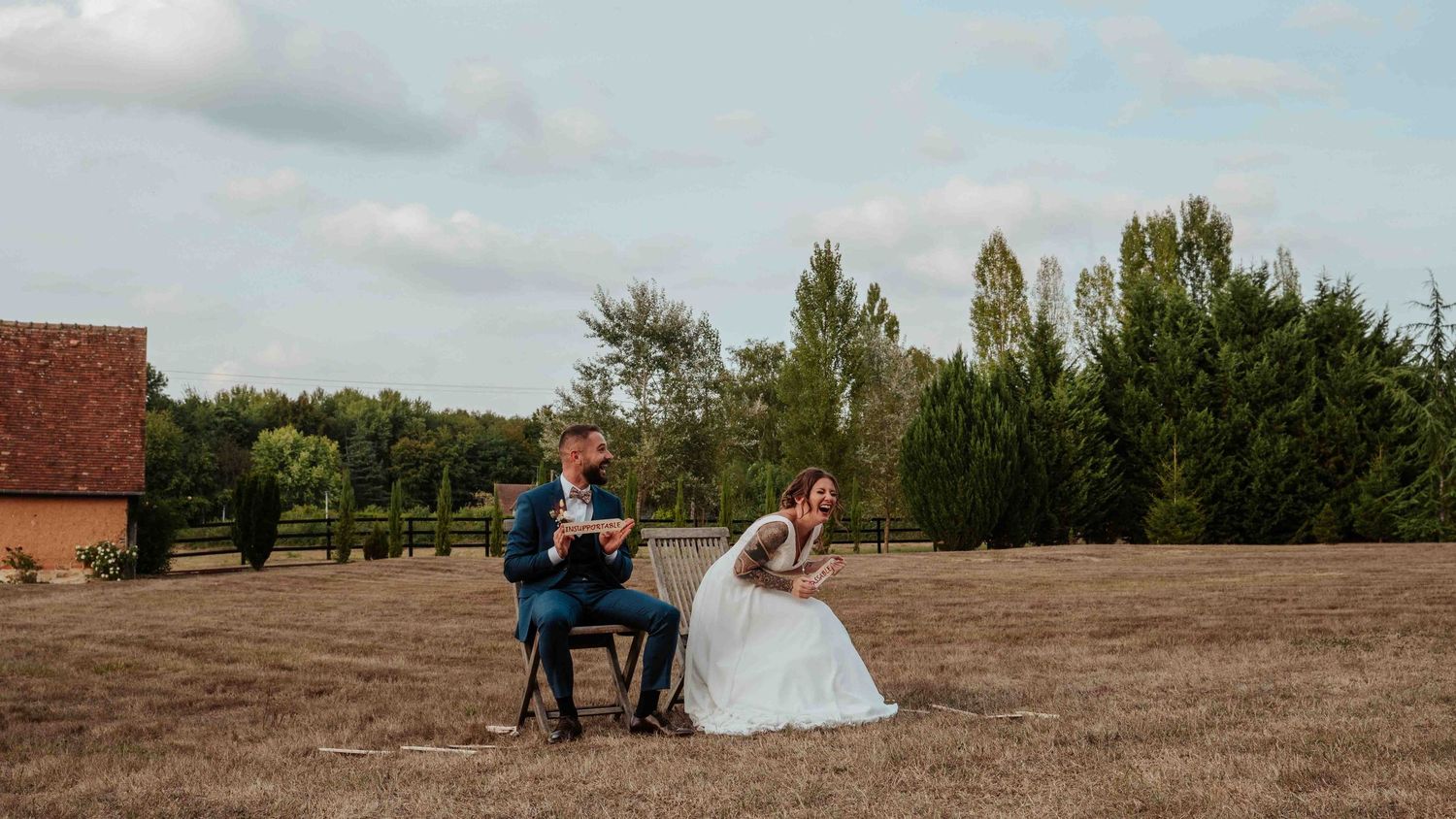 Les mariés, assis sur des chaises, échangent leurs vœux dans un champ doré lors d'une cérémonie de mariage en plein air.