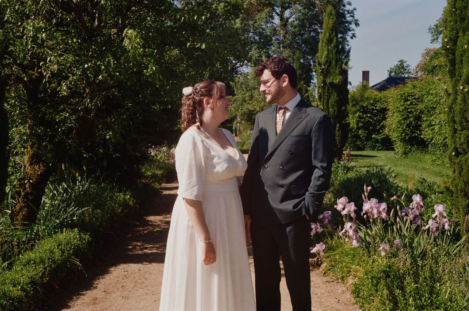 Mariage en argentique – Portrait des mariés dans un jardin fleuri – Photo douce et naturelle prise sur pellicule.