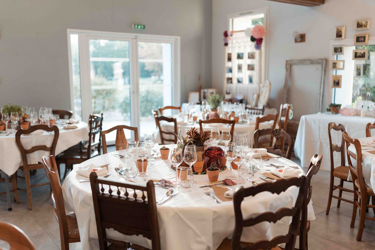 Élégante salle à manger pour réception de mariage, avec des tables rondes nappées de lin blanc et des chaises en bois.