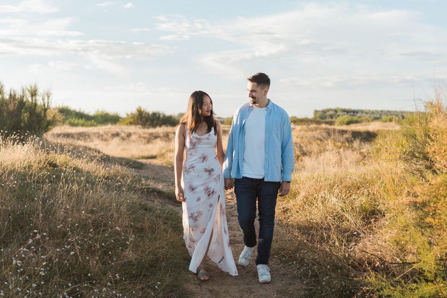 Balade romantique en bord de mer – Promenade main dans la main au coucher du soleil sur un sentier côtier.