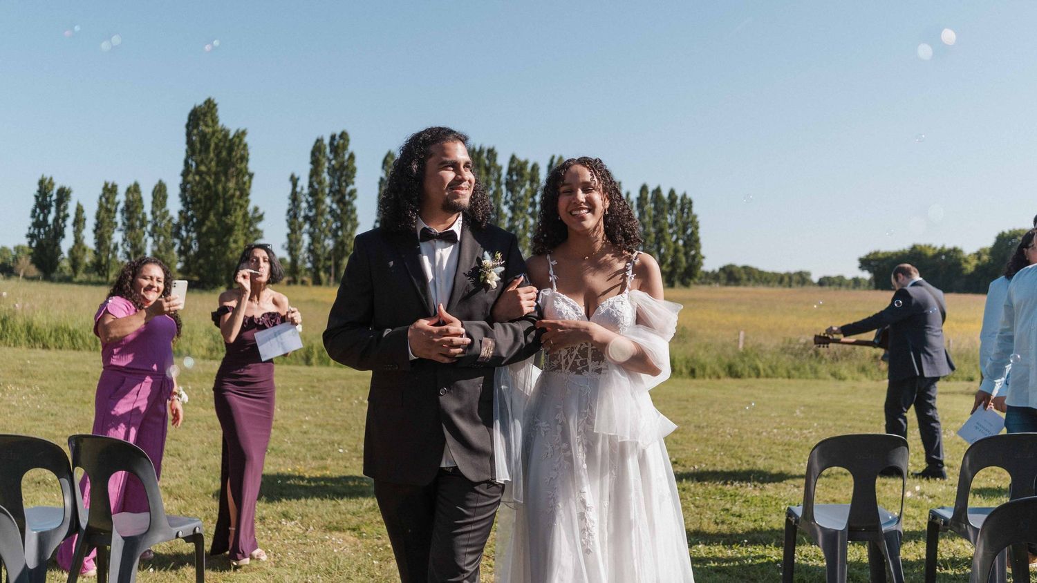 Les jeunes mariés descendent l'allée extérieure après la cérémonie de mariage sous les acclamations des invités.