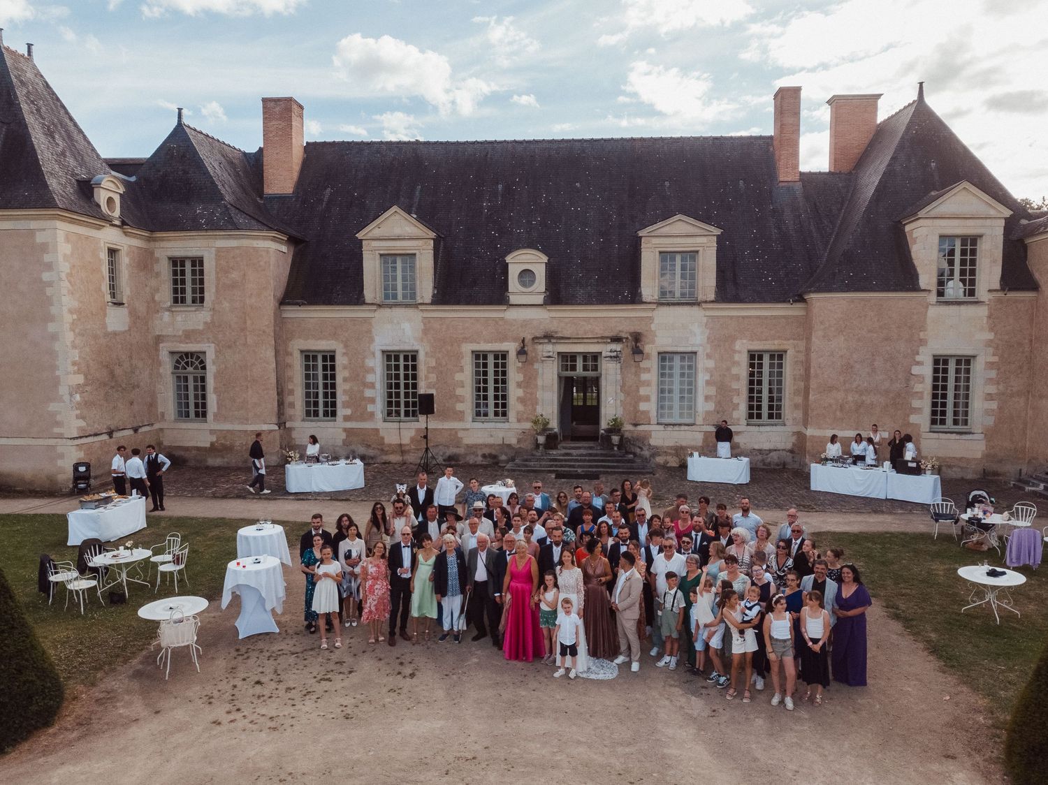 Photo de mariage au drone – Vue aérienne des invités devant le Château de la Perrière. Scène de groupe capturée en hauteur.