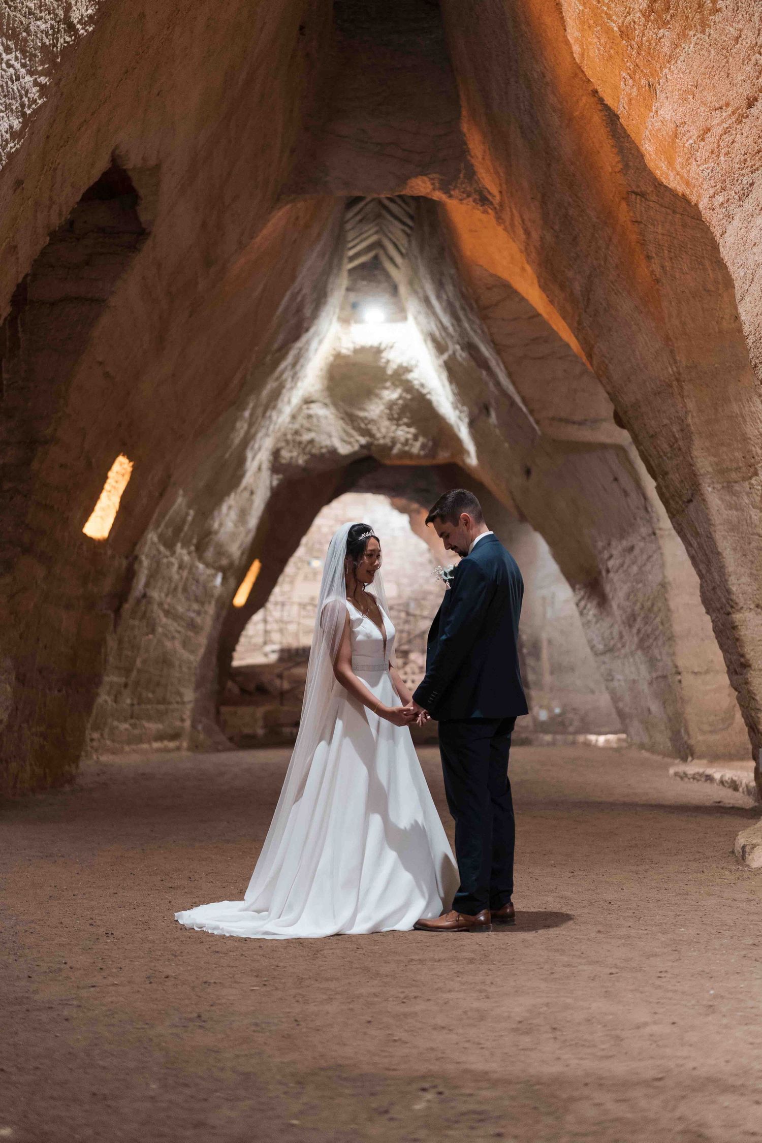 Les mariés se tiennent la main dans un lieu de cérémonie de mariage époustouflant, une ancienne grotte.