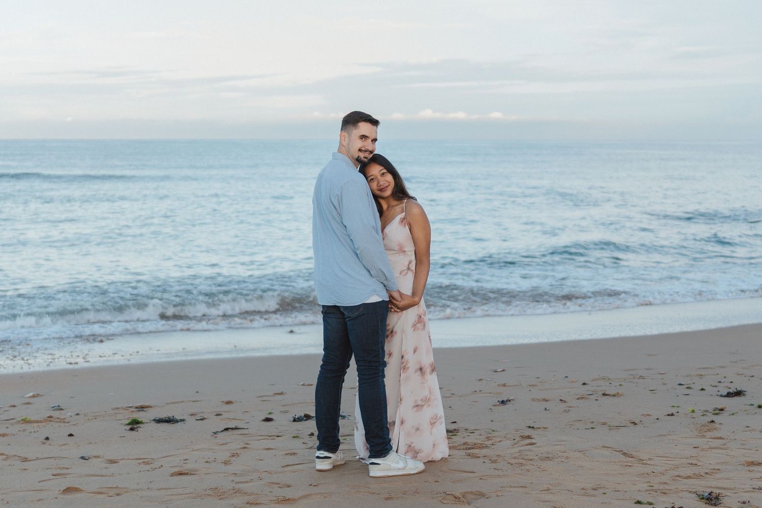 Moment complice d’un couple enlacé sur la plage aux Sables d’Olonne lors d’une séance engagement