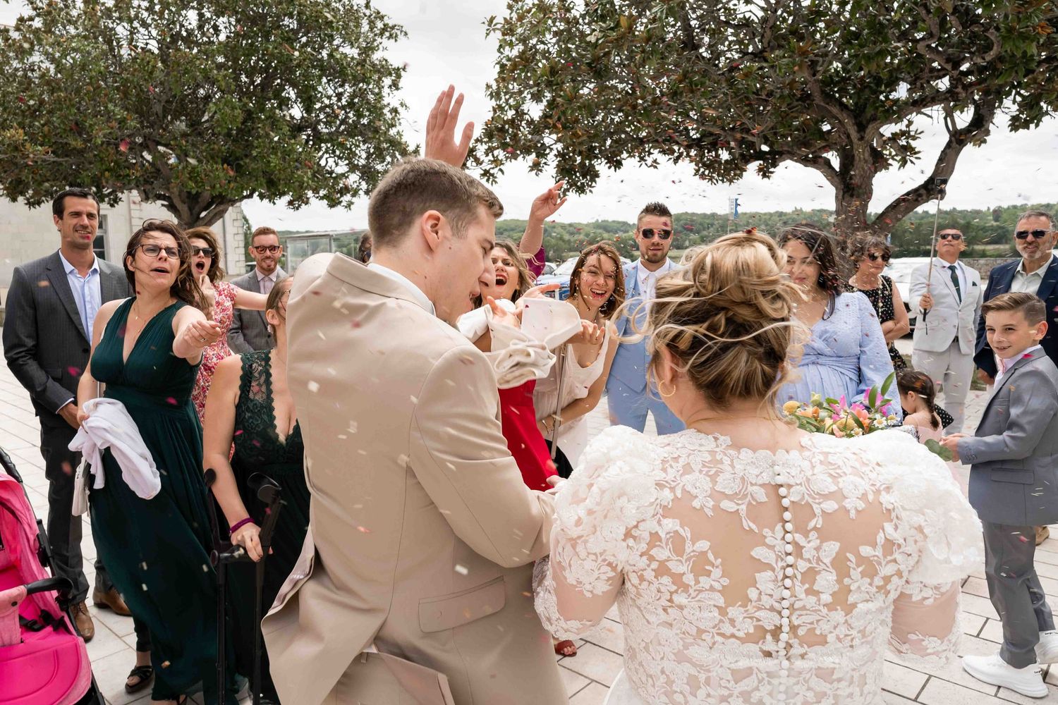 Des invités joyeux célèbrent les jeunes mariés avec des confettis lors de la réception de la cérémonie en plein air.