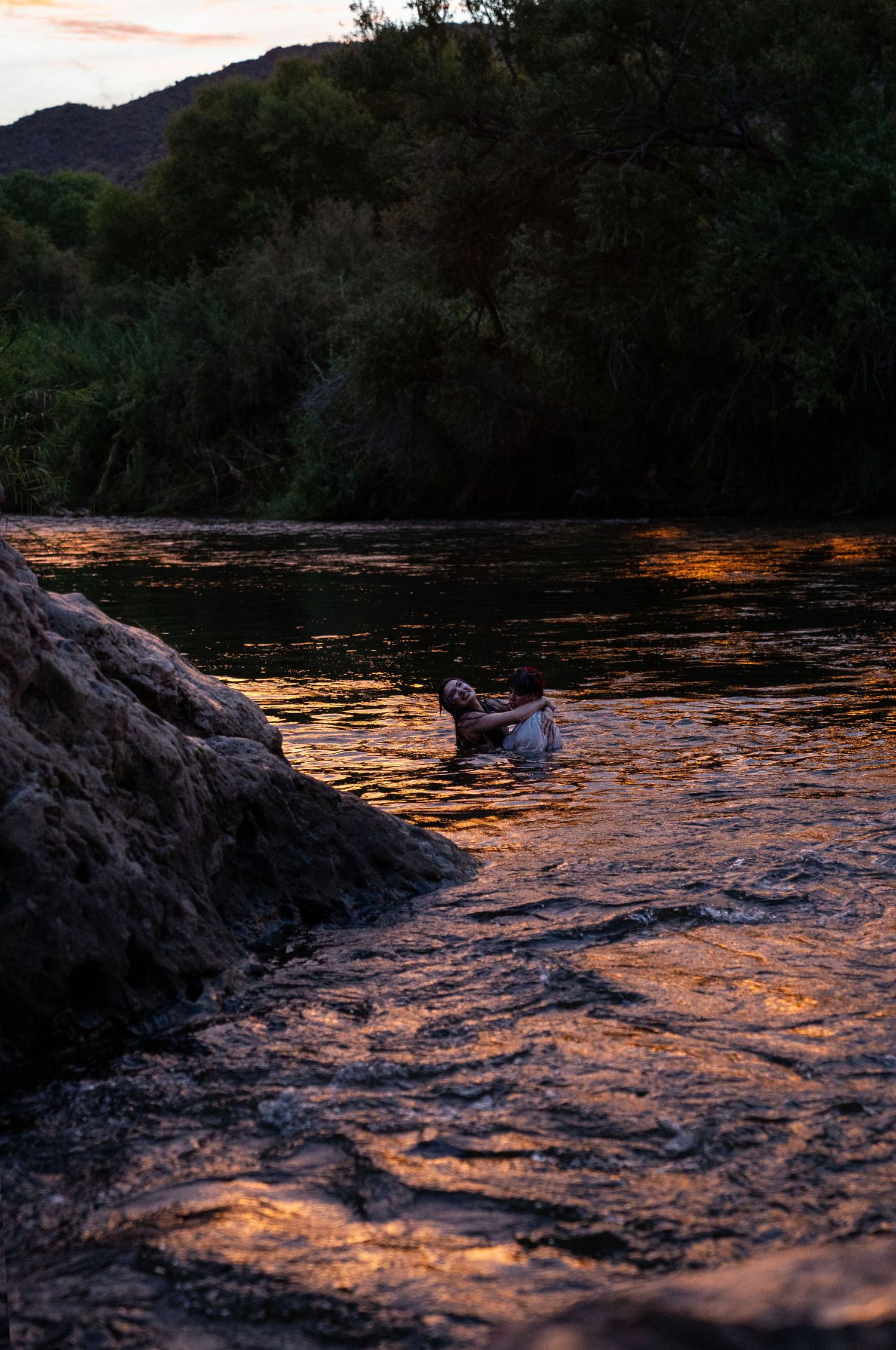 Person wading in river with warm golden sunset reflections on water. Fantasy photoshoot. Arizona photographer.