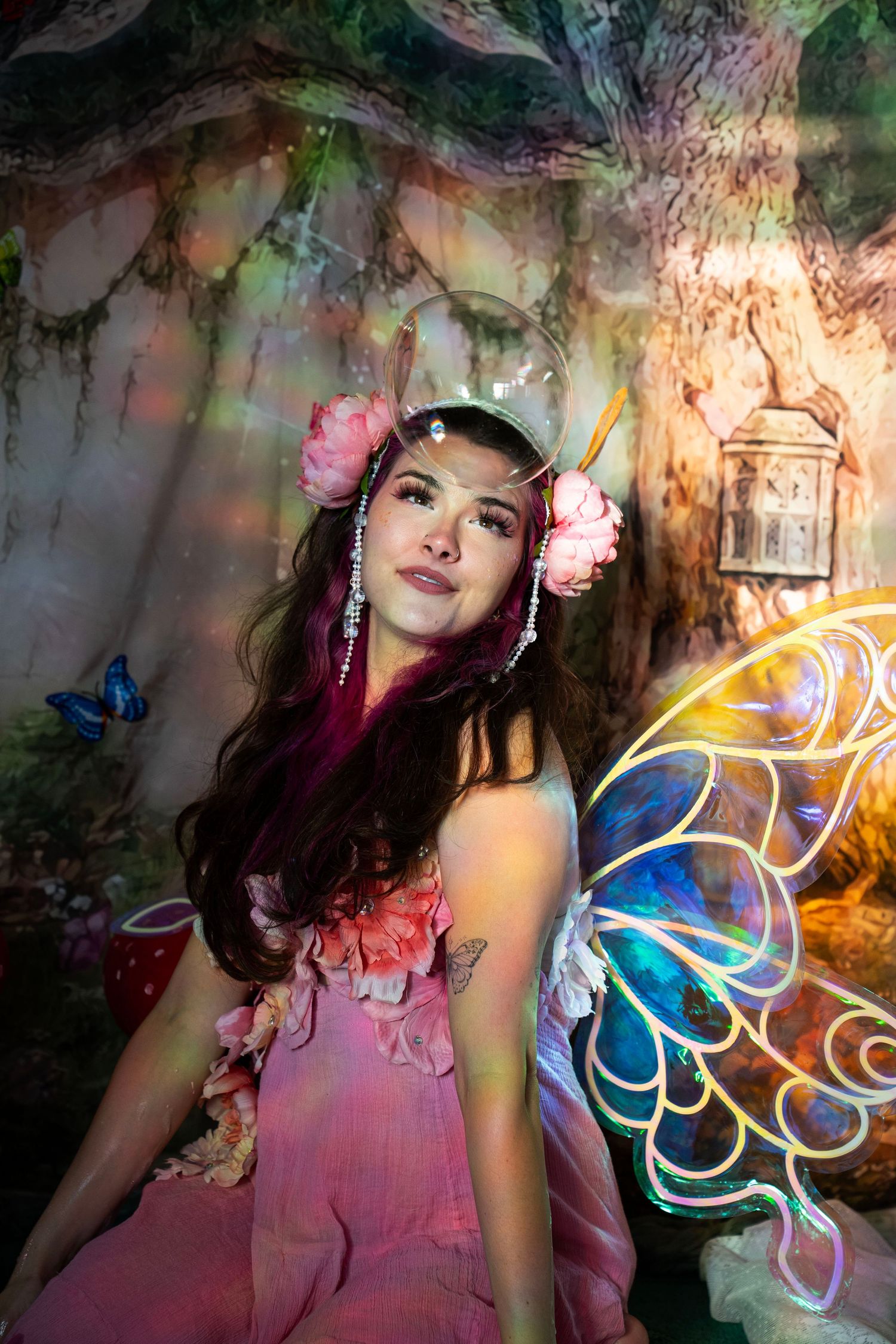 Woman in fairy costume with colorful butterfly wings in an enchanted forest backdrop. Fantasy Photoshoot