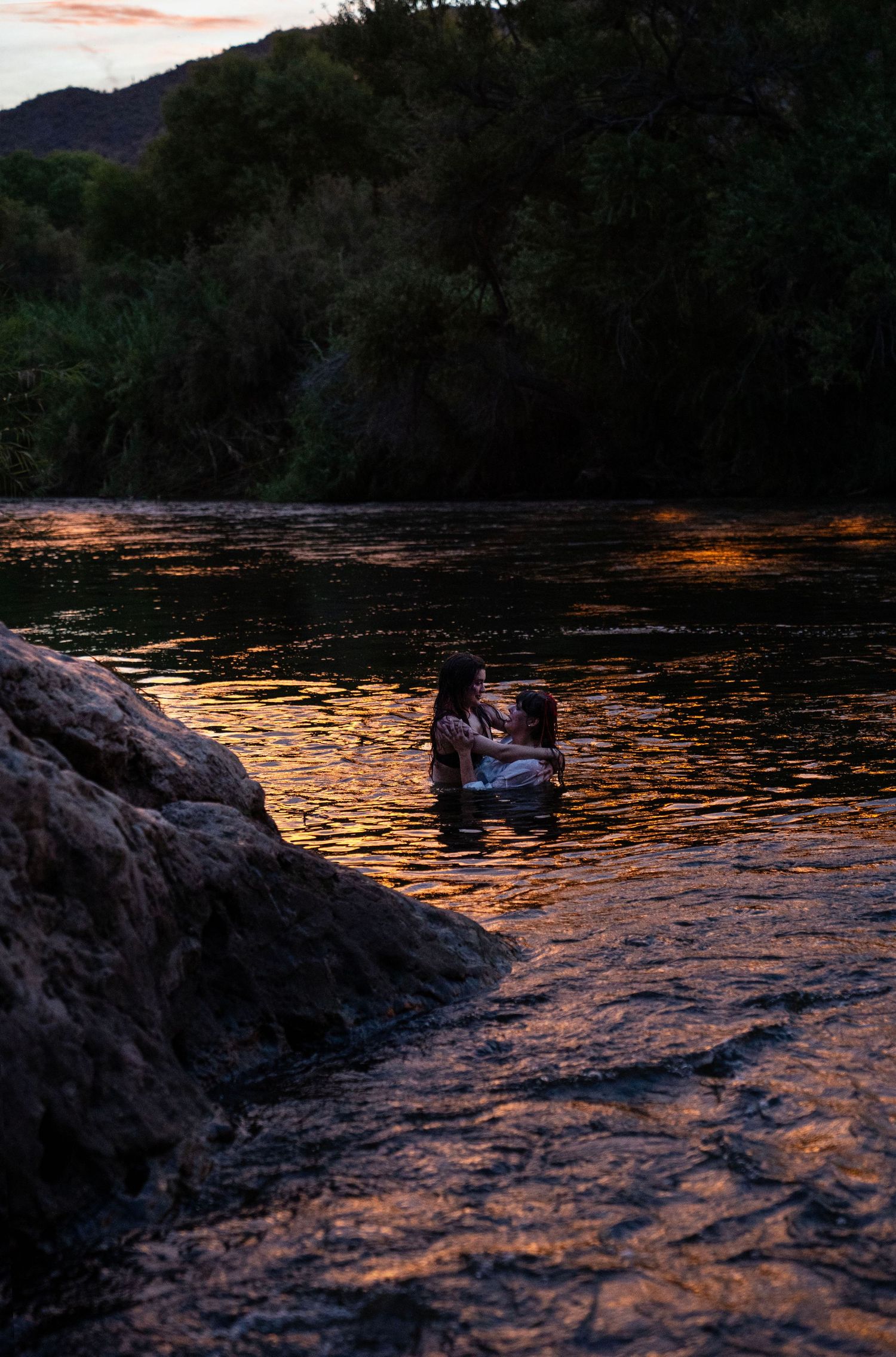 Couple embracing in river with warm golden sunset light reflections. Fantasy photoshoot. Arizona photographer.